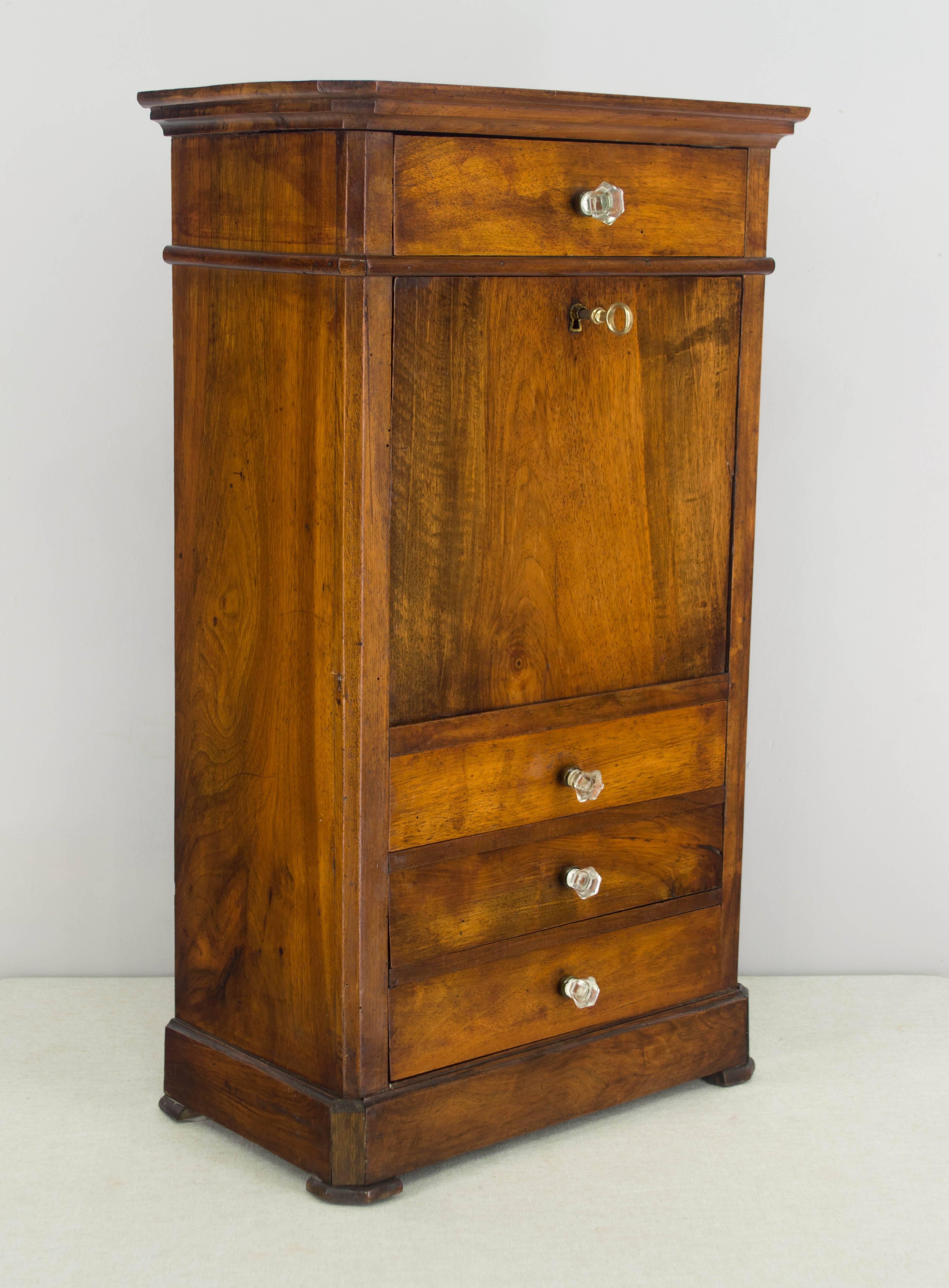 19th century Louis Philippe period miniature secretaire a abbattant made of solid walnut with French polish finish. Three dovetailed drawers with glass knobs and a pull down 