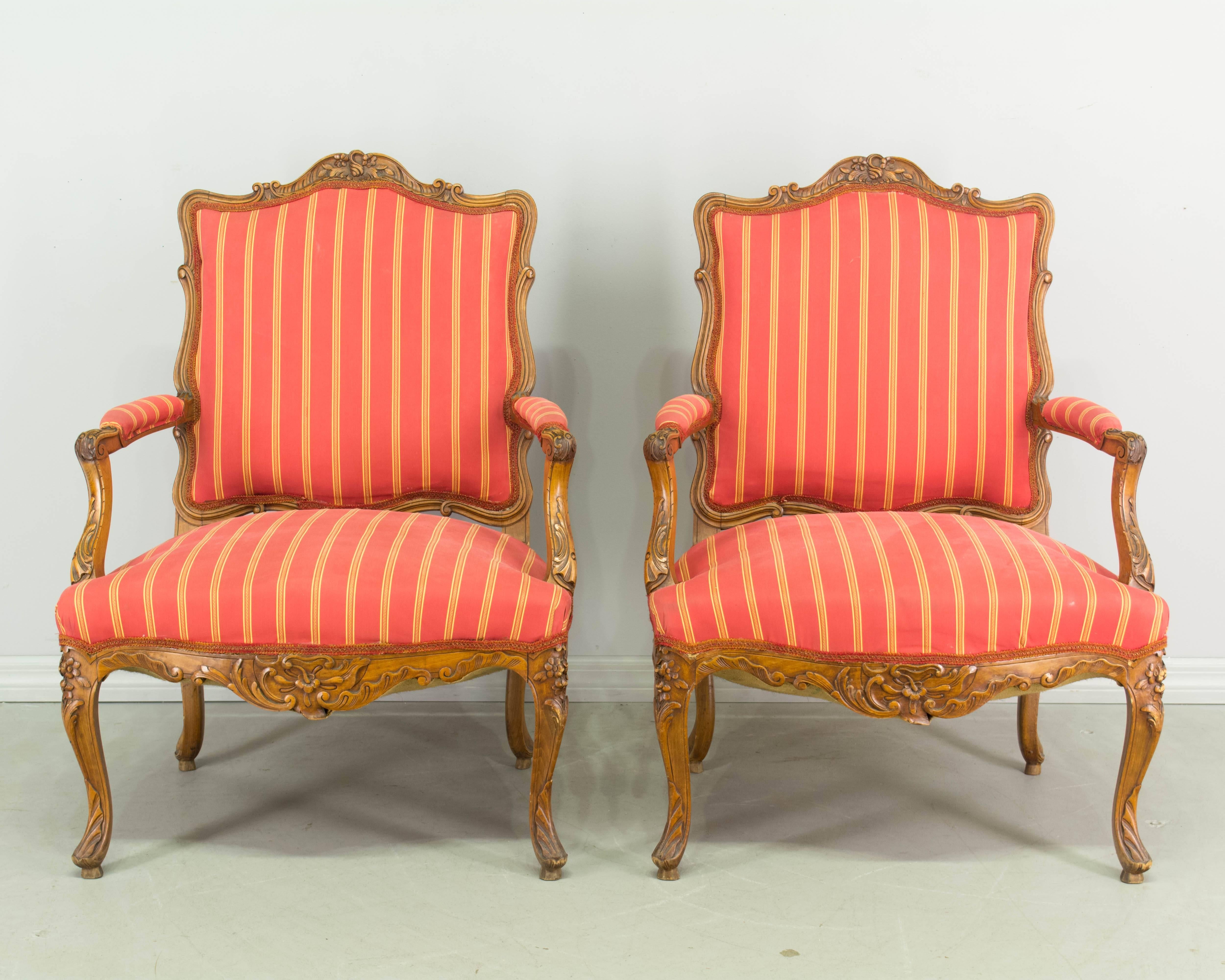 A suite of four Louis XV style chairs, including two fauteuils and two side chairs. Walnut frames with fine, hand-carved details. Sturdy and comfortable. Upholstery is old with one of the side chairs having a stained seat. 
Armchairs: 28" W x