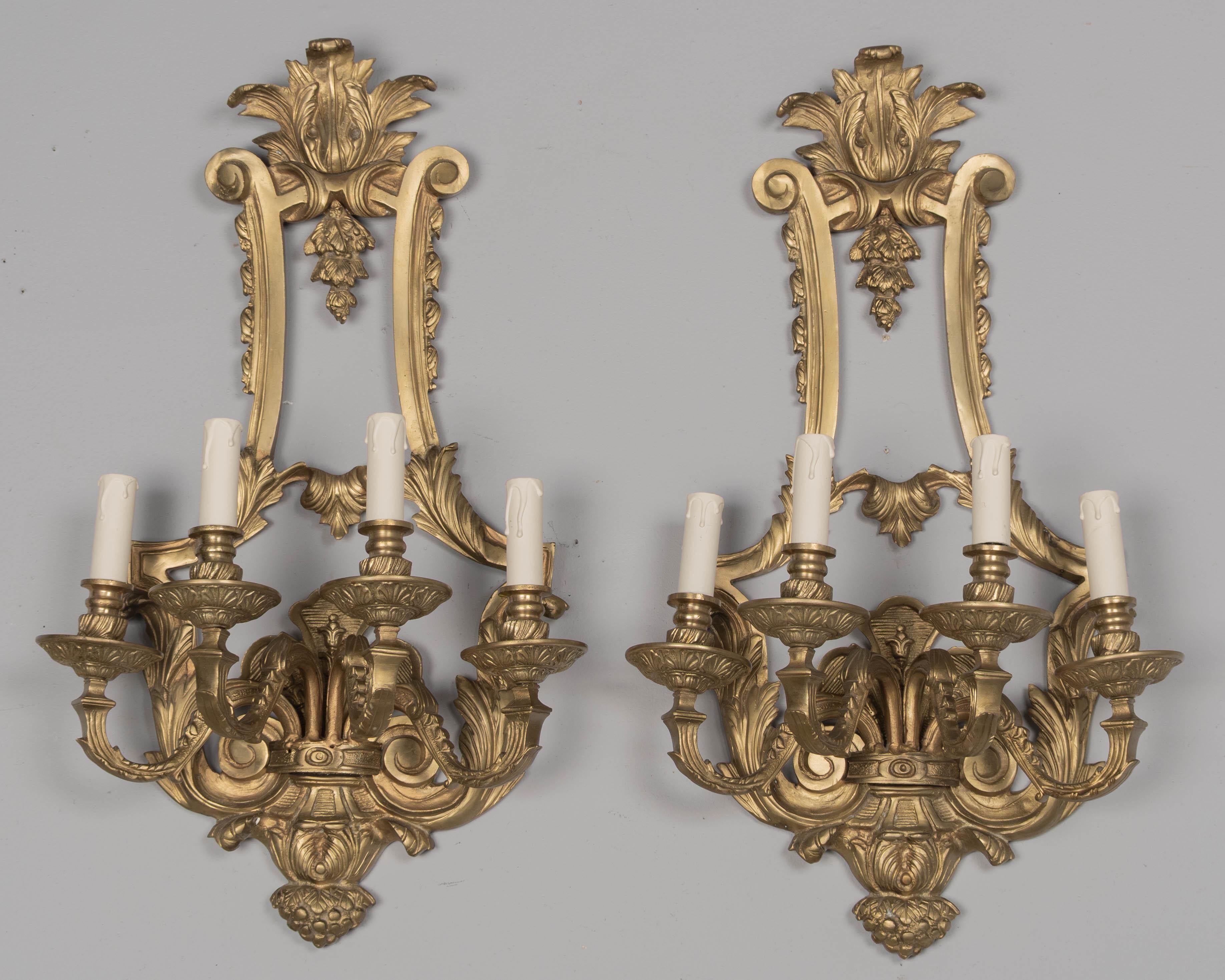 A pair of Italian Renaissance style cast bronze wall sconces, each with four scrolled arms. Large, heavy ornate sconces, nicely detailed with large scrolls and acanthus leaves. Rewired with new sockets. Original wood candle covers. Circa 1940s