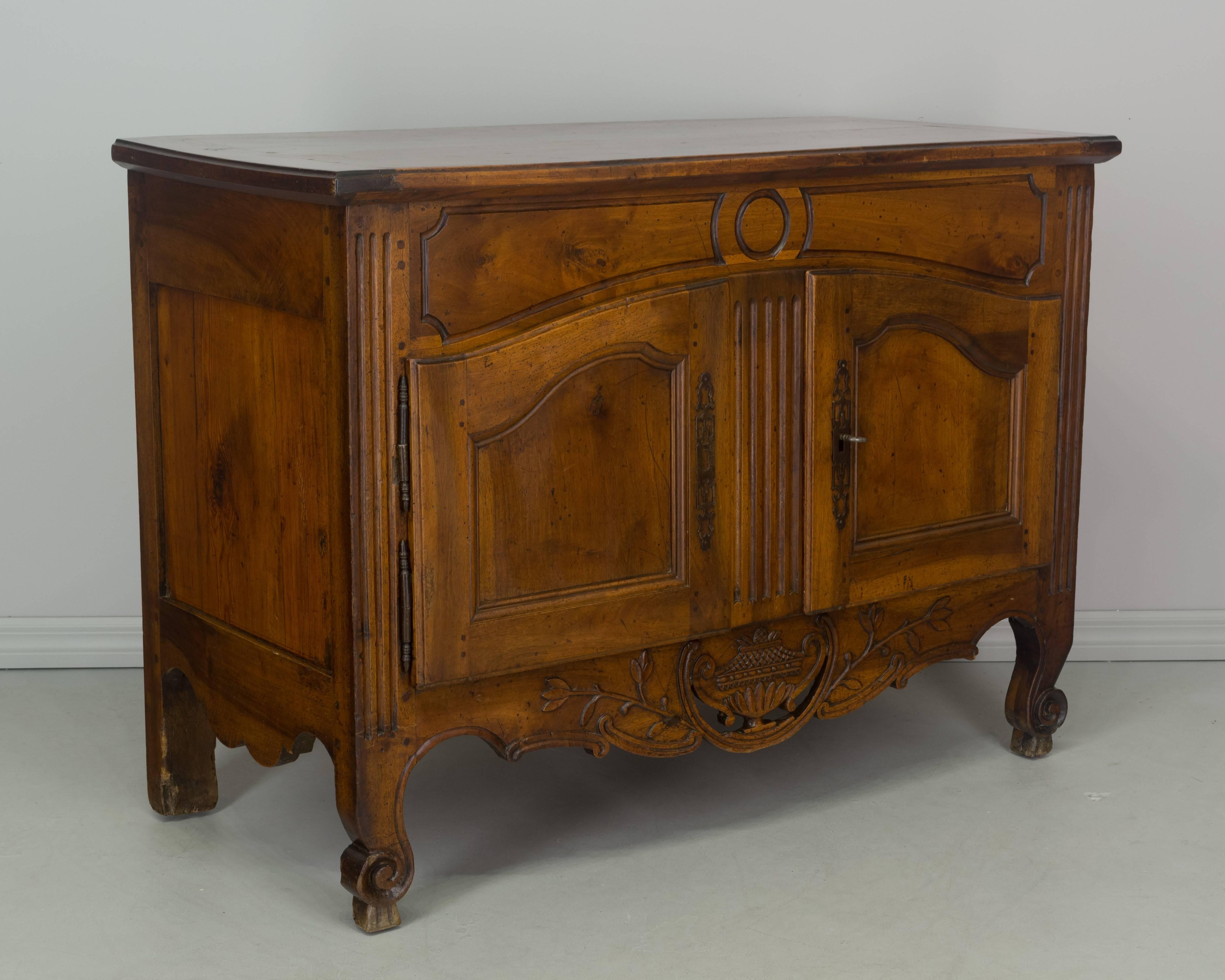 A fine early 19th century Louis XV Provençal buffet made of solid walnut with pine as a secondary wood. The top of this buffet slides forward to reveal a removable original dough box. Nice proportions and hand carvings including a pierced apron.