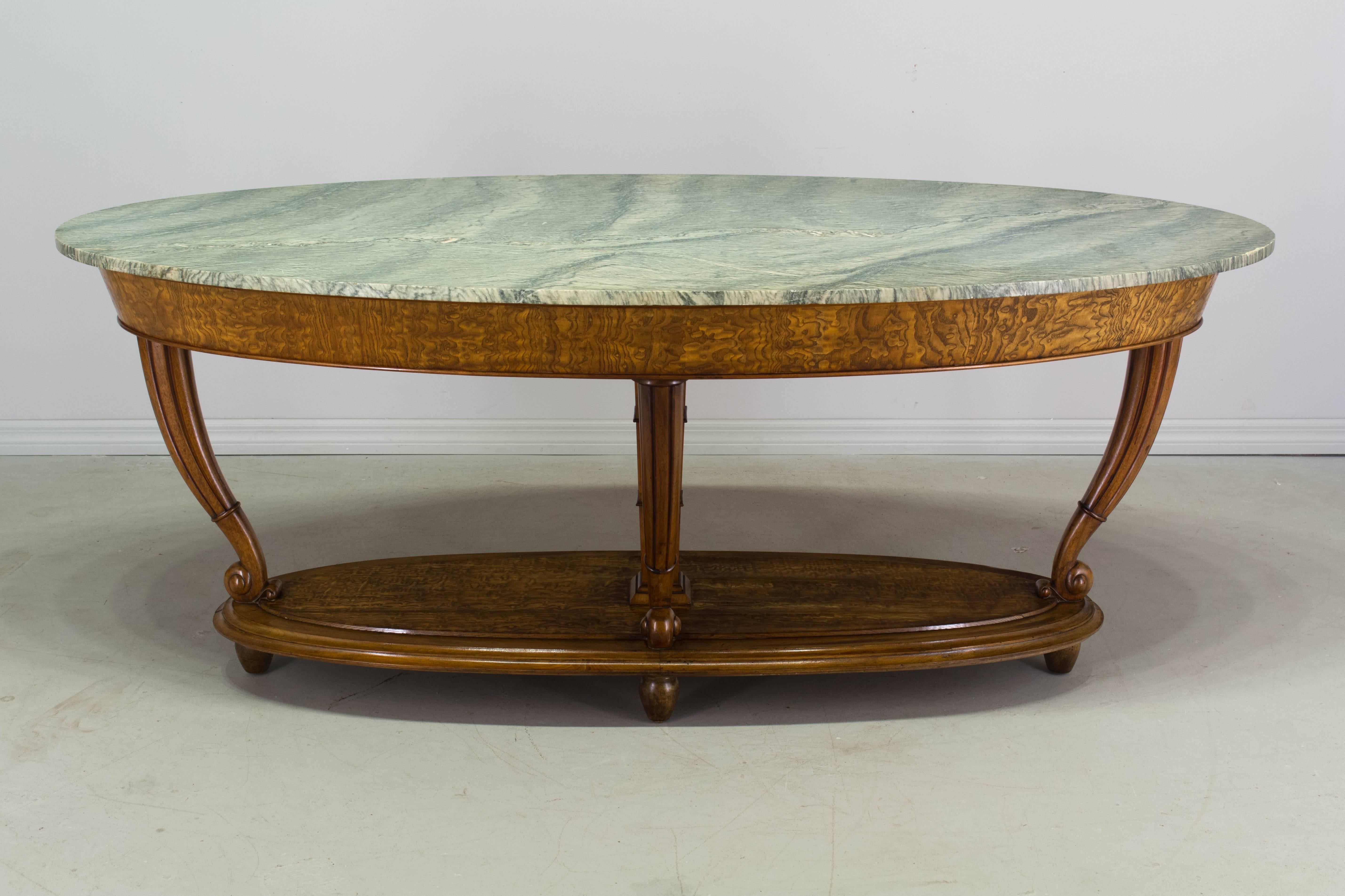 A fine Italian oval center table with an exquisite cipollino marble top. The frame is made of walnut with solid carved walnut legs and bun feet. The apron and the top of the base are burl of elm veneer with a wavy wood grain that mimics the ocean