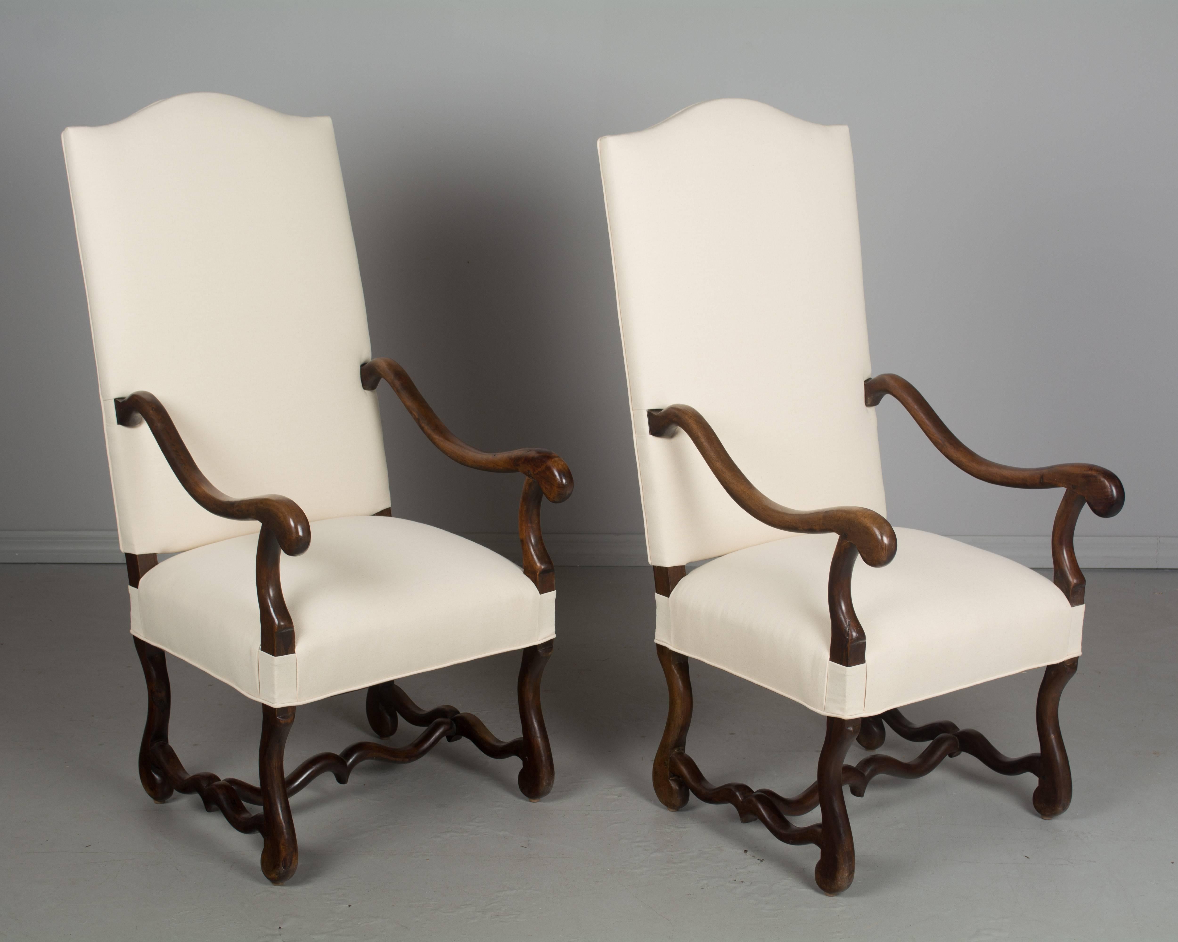 A pair of 19th Century Os de Mouton style fauteuils, or arm chairs, made of walnut. Comfortable seating with sturdy frames and pegged construction. Newly upholstered.
