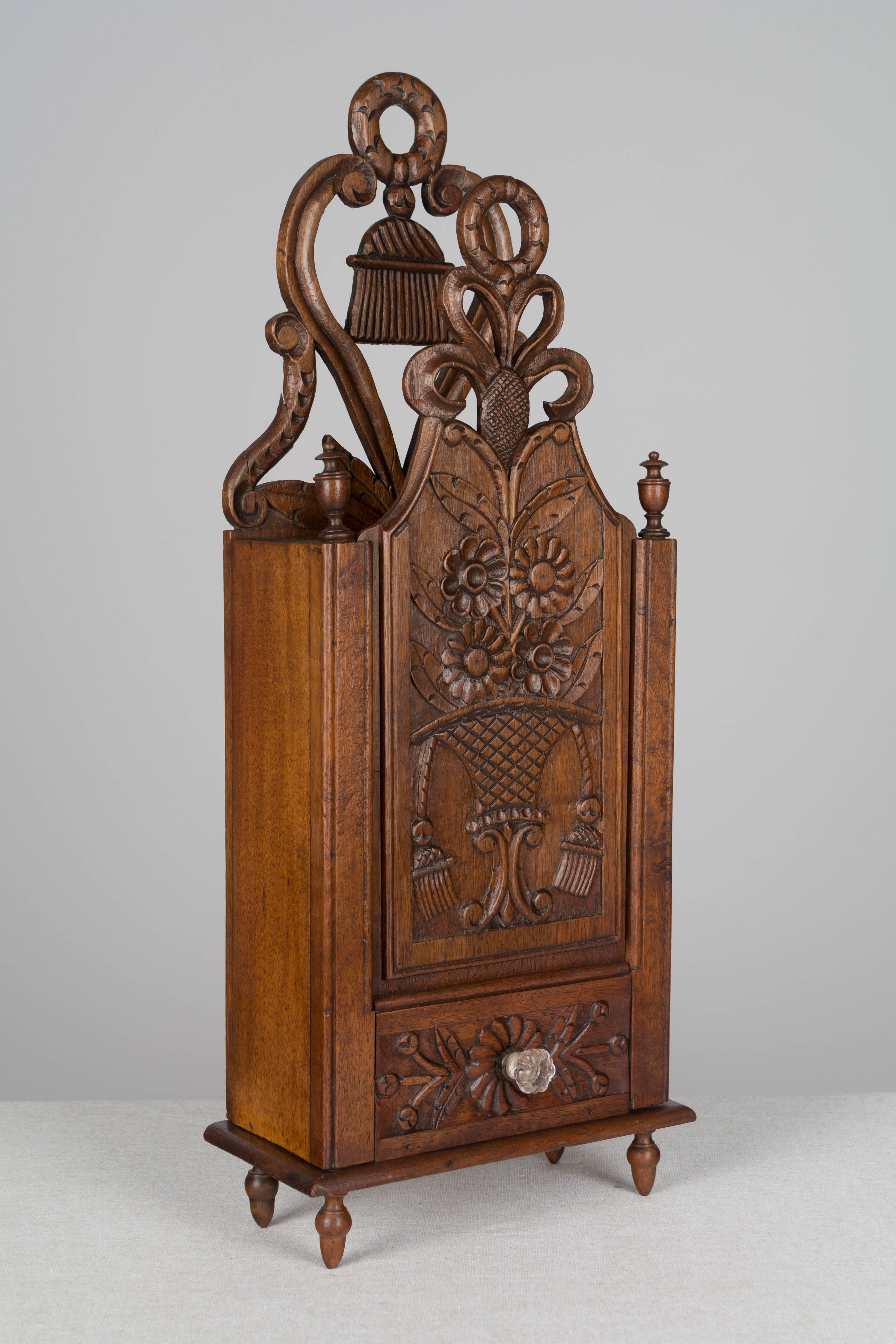 A beautiful French fariniere from Provence, made of walnut with fine hand-carved details and an elaborate pierced crest. Nicely detailed with tiny turned finials and feet and a false drawer with glass knob. A fariniere is a sliding paneled box that