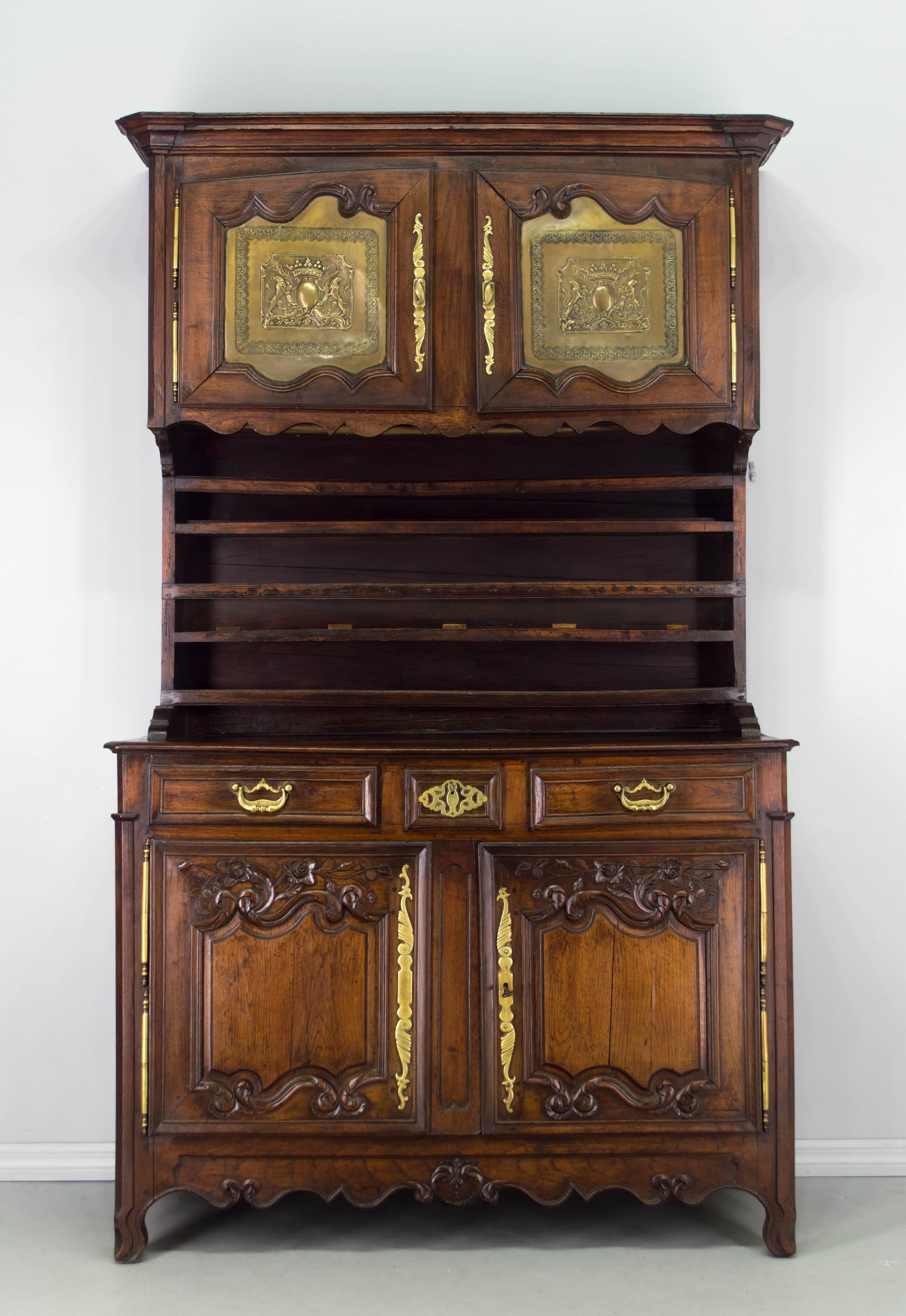 A vaisselier from the Manche province (north of Normandy) made of solid chestnut. Buffet has two beautiful hand-carved doors and three dovetailed drawers. Upper cabinet has two doors with brass panels embossed with the coat of arms of the local