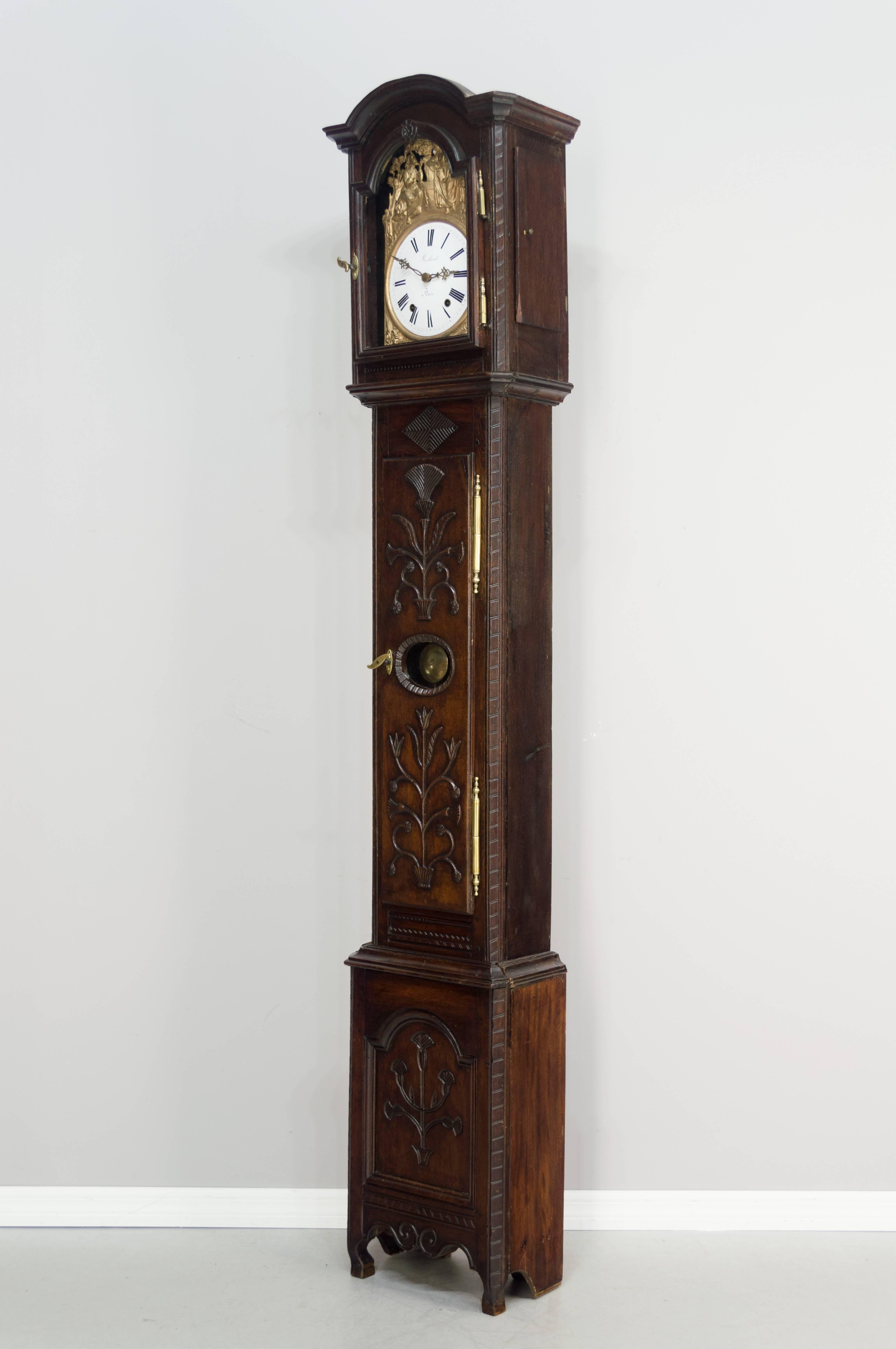 A good 18th century tall case clock with a later Morbier movement in working condition. The case is made of oak with floral carvings and original brass hardware and with a waxed patina. The glass panes are old. Late 19th c. seven day Morbier