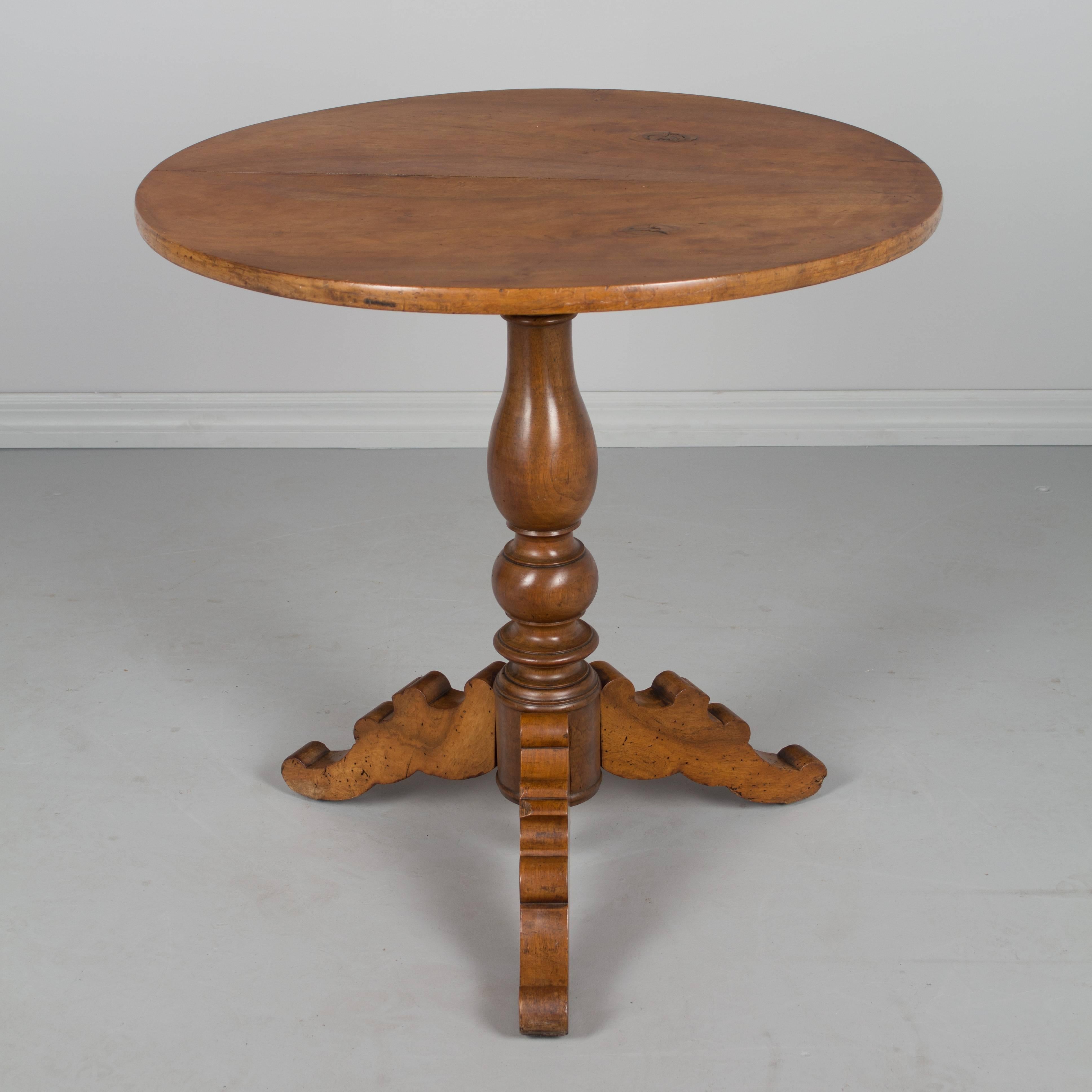A 19th century French Louis Philippe gueridon, or circular side table, made of solid walnut. Turned pedestal base with shaped tripod legs. Tabletop is made of two bookmatched planks of walnut with prominent knots in the wood. In two pieces, the top