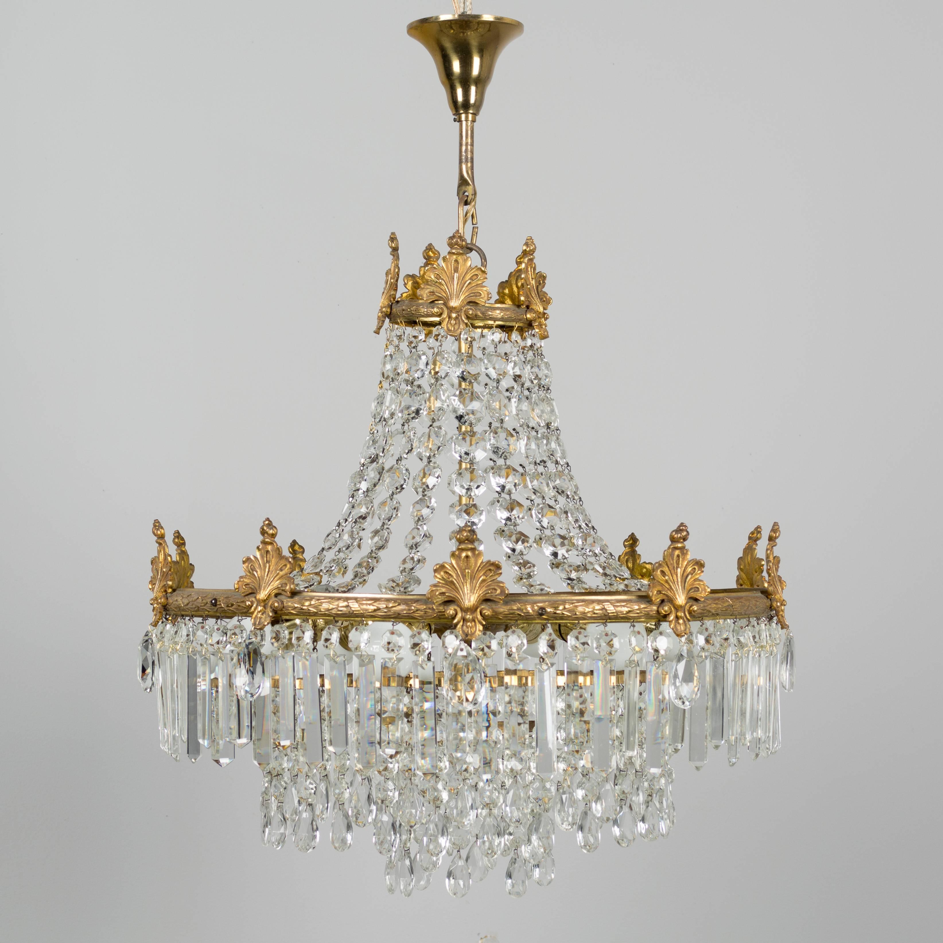 A French Empire style six-light crystal chandelier with brass frame. A beautiful waterfall form with multiple strands of faceted bead chains and three tiers of hanging prisms. The brass has been cleaned and the chandelier is rewired. More photos