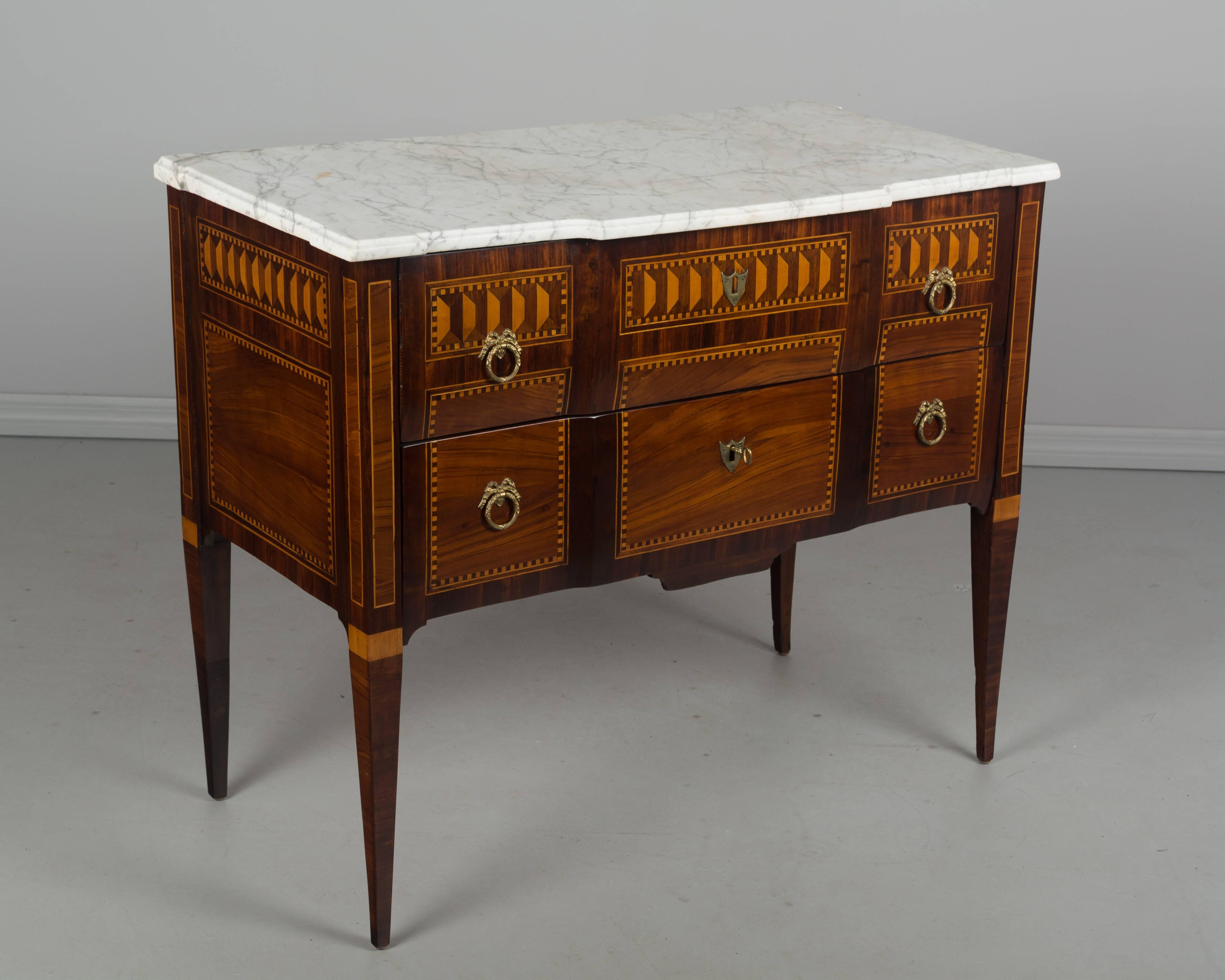 An 18th century French Louis XVI marquetry commode with various veneers, mostly walnut and mahogany. Nice proportions with slender tapered legs. Pegged construction with mortise and tenon joints. French polish finish. Two dovetailed drawers with