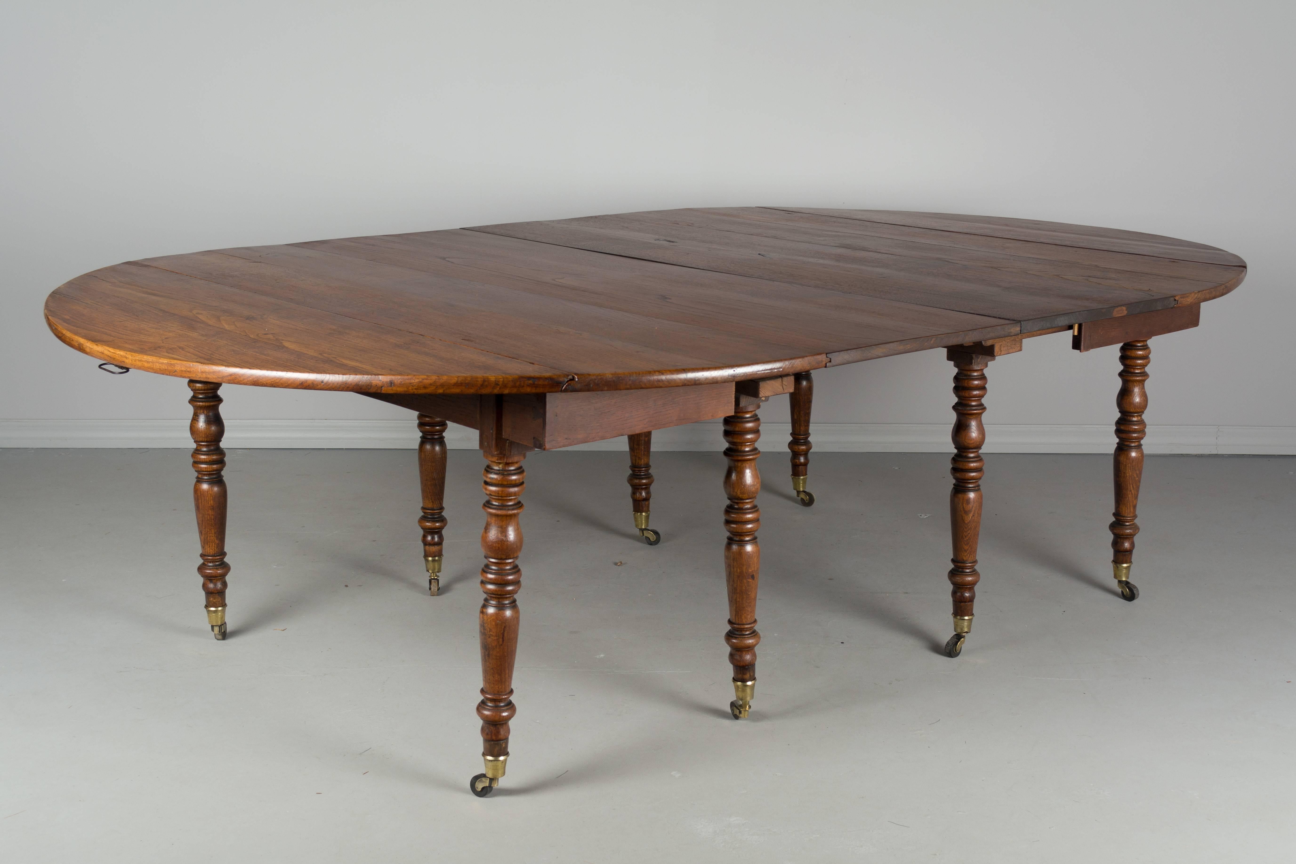 A 19th century Louis Philippe drop-leaf dining extension table made of chestnut. Eight turned legs ending in brass sabots and castors. Six new leaves of solid chestnut. Waxed finish. This table when fully open is almost 15 feet long and seats 18-20