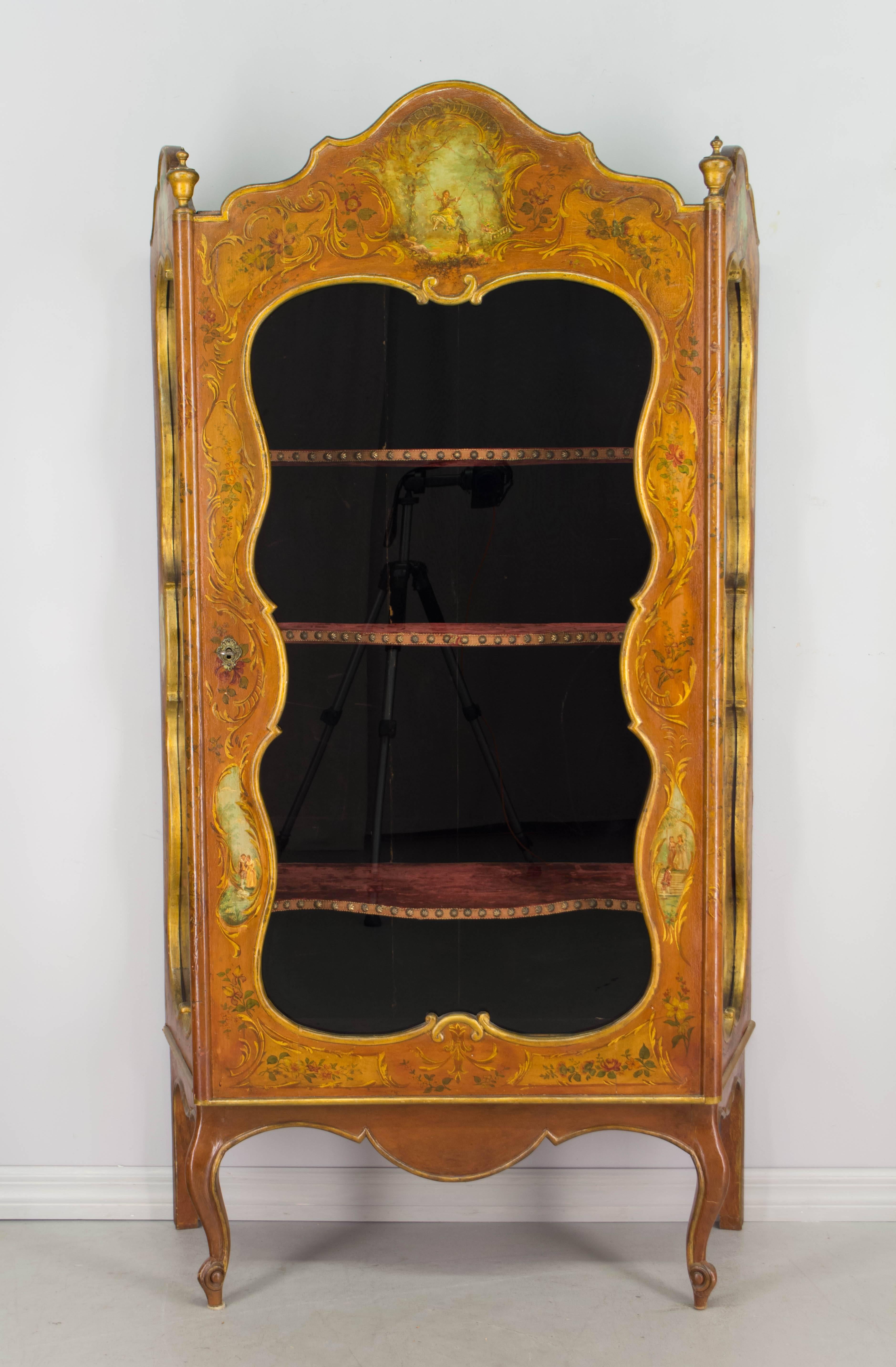 An original polychrome painted vitrine with three shaped adjustable shelves recovered with burgundy velvet, romantic scenes, signed on the top 