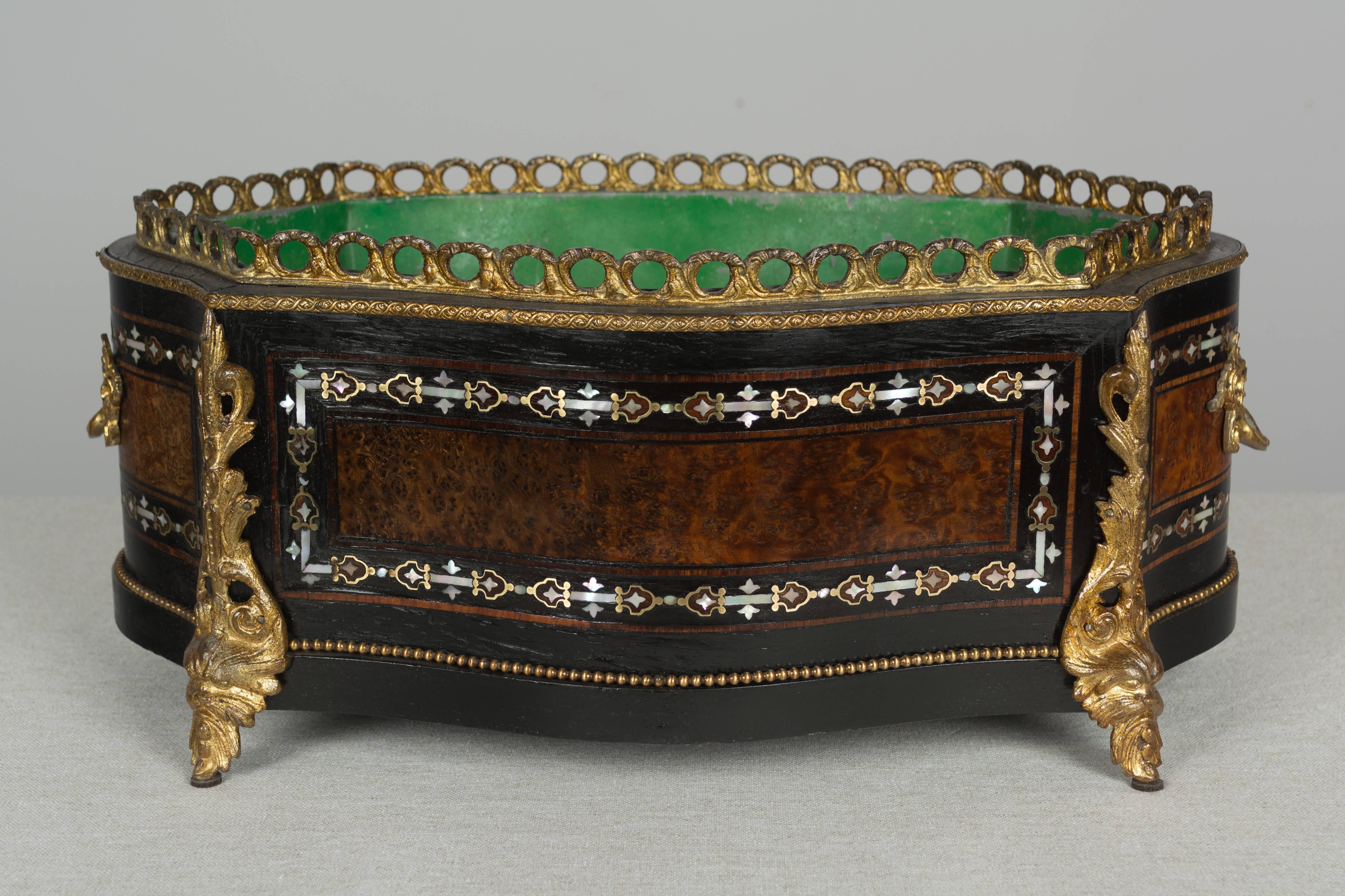A fine 19th century Napoleon III marquetry jardiniere with mother of pearl inlay, ebonized wood and burl of elm veneer. Bronze mounted with two handles, gallery and corner ornaments. Removable zinc liner with green painted interior. A beautiful