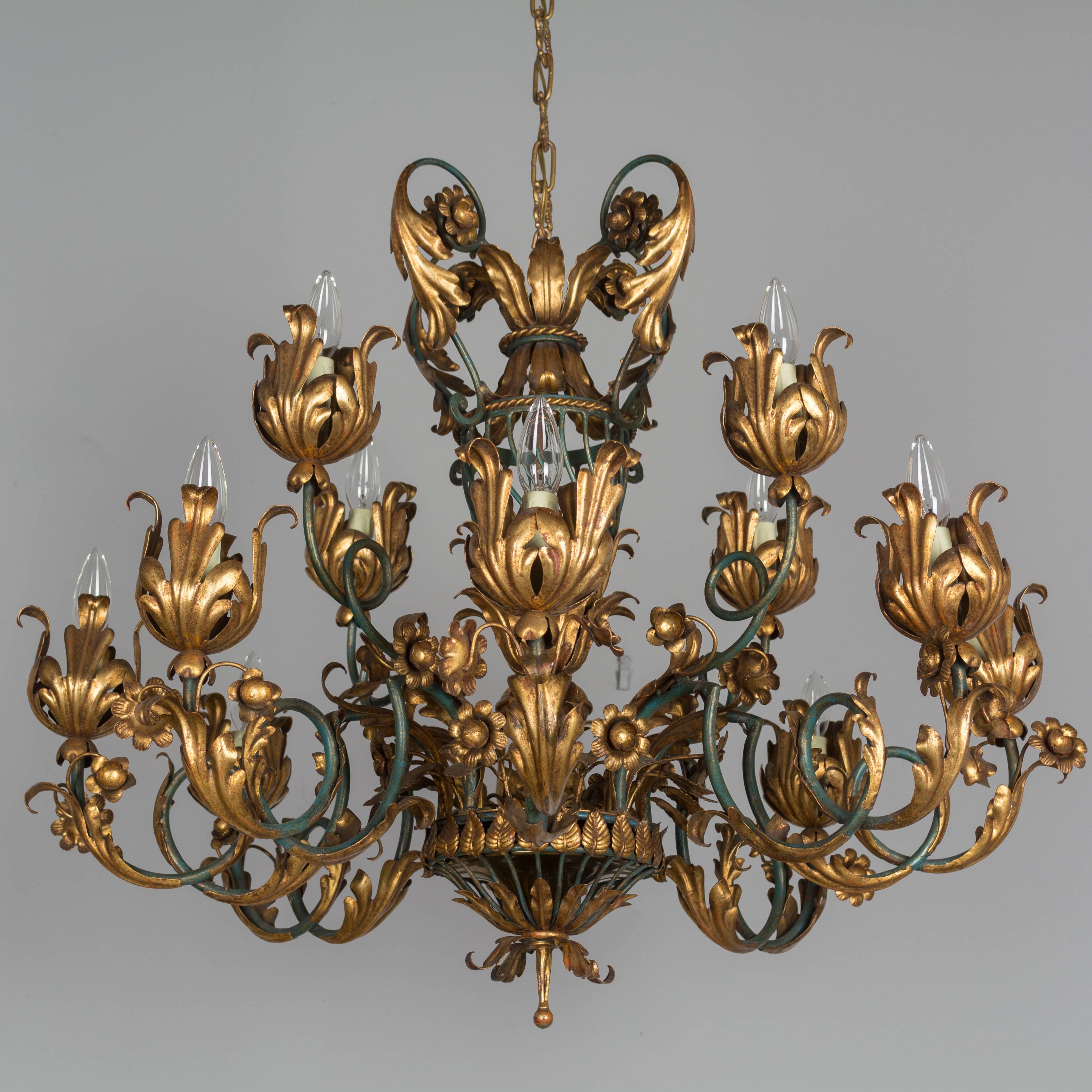 A French 1940s parcel-gilt twelve-light wrought iron chandelier. Elaborately detailed, with large gilded tole acanthus leaves and rosebuds. Rewired and shown with 25 watt torpedo bulbs (not included). Ground wire will be need it to install. 