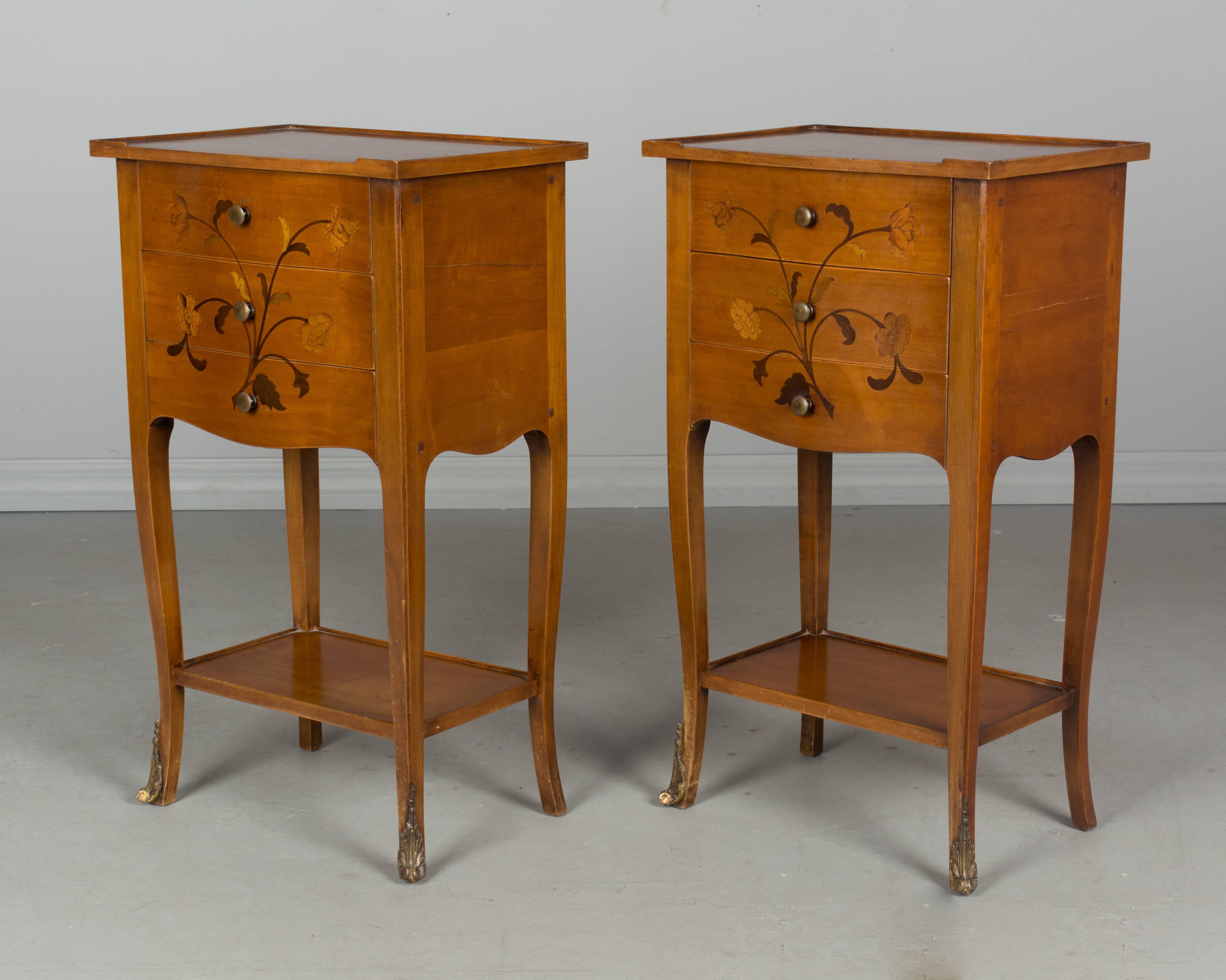 Pair of French Louis XV style marquetry side tables or nightstands made of cheerywood with inlaid veneer of walnut. Two dovetailed drawers with brass knobs. Slender curved legs with decorative brass sabots.