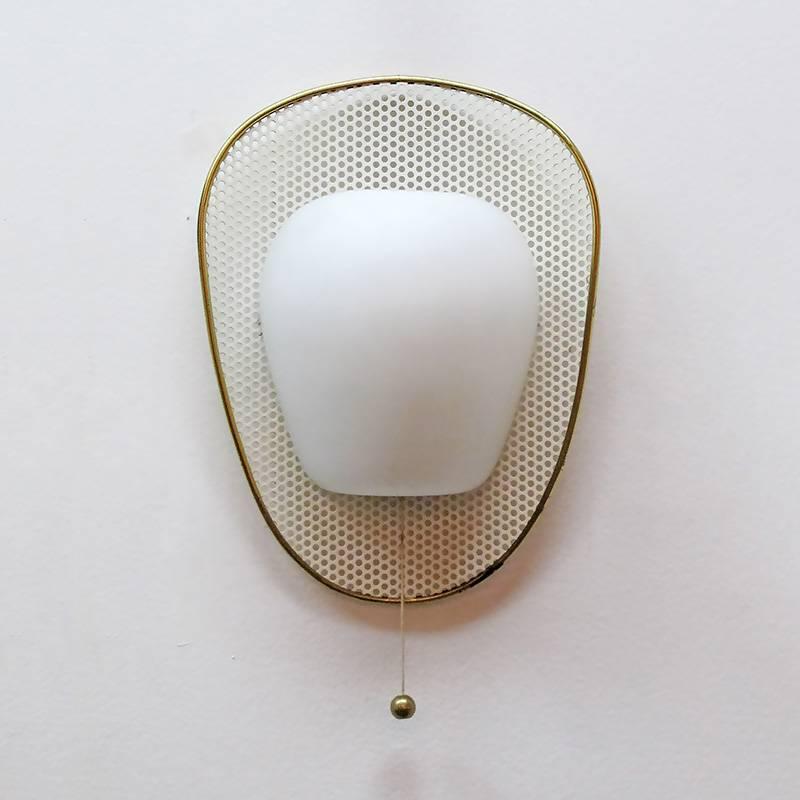  French wall light attributed to Mathieu Mategot, opaline glass shell on a perforated, enameled metal shield with brass rim, individual brass ball on/off switch.

One available, two have sold. 