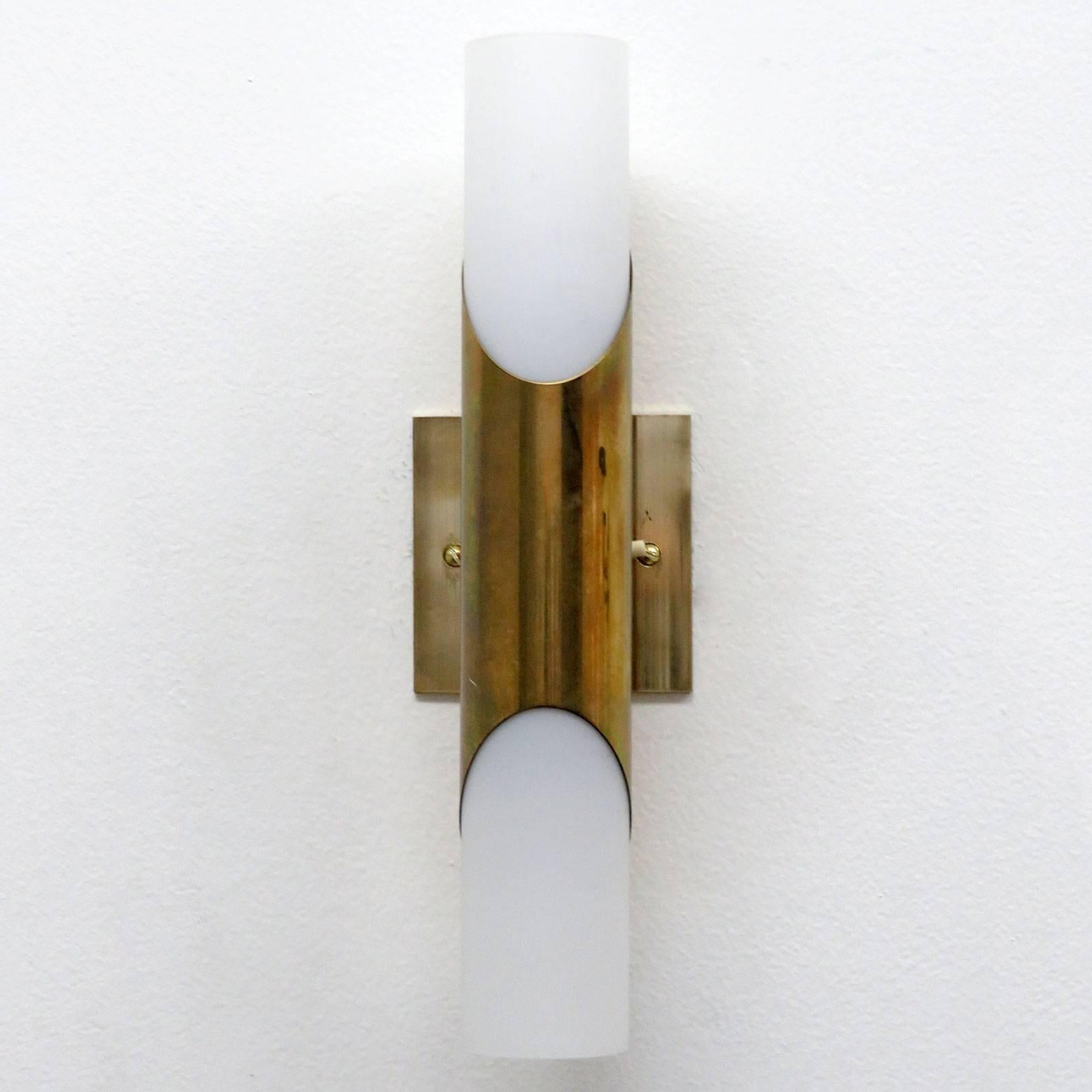 Simply elegant pair of 1970s brass wall lights by Neuhaus Leuchten, Germany, with two light sources each behind respective cased opaline glass tubes, individual on/off switch at each light, custom solid brass plate to cover US junction boxes.