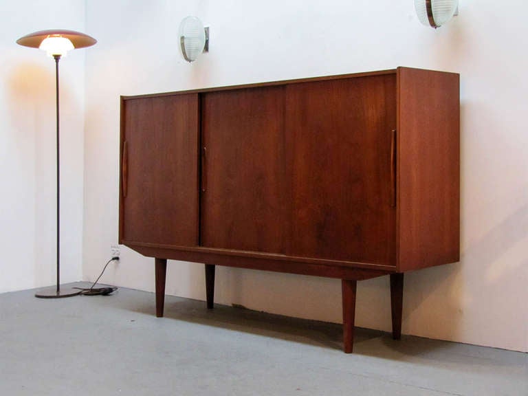 Wonderful tall 1950s Swedish teak credenza by Royal Board, Sweden, with three sliding doors, featuring three shelves in the side compartments and a mirrored shelf setup with three drawers in the center compartment.