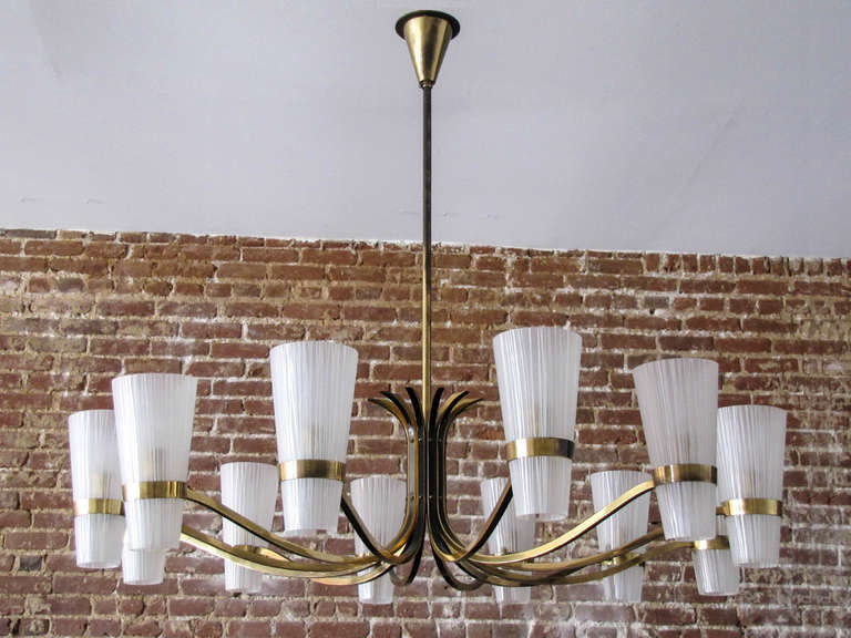 Stunning large decorative German twelve-arm brass chandelier, with two-tone brass arms and textured glass cups.
