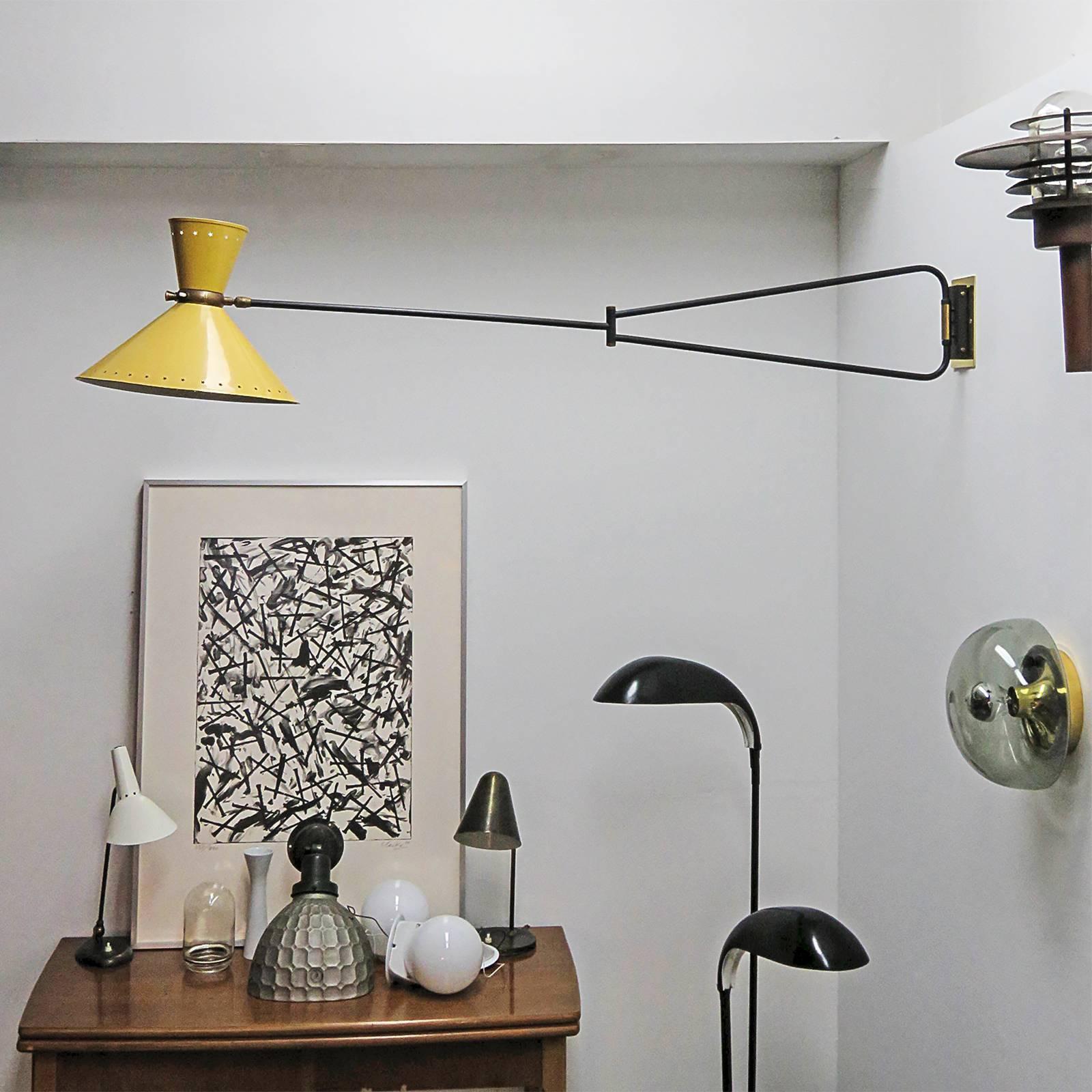 stunning large-scale articulate swing arm wall light by Rene Mathieu for Lunel, double cone lamp shade in original yellow enamel with two light source (up/down) and individual on/off switches at the center of the shades, brass accent to the arm and