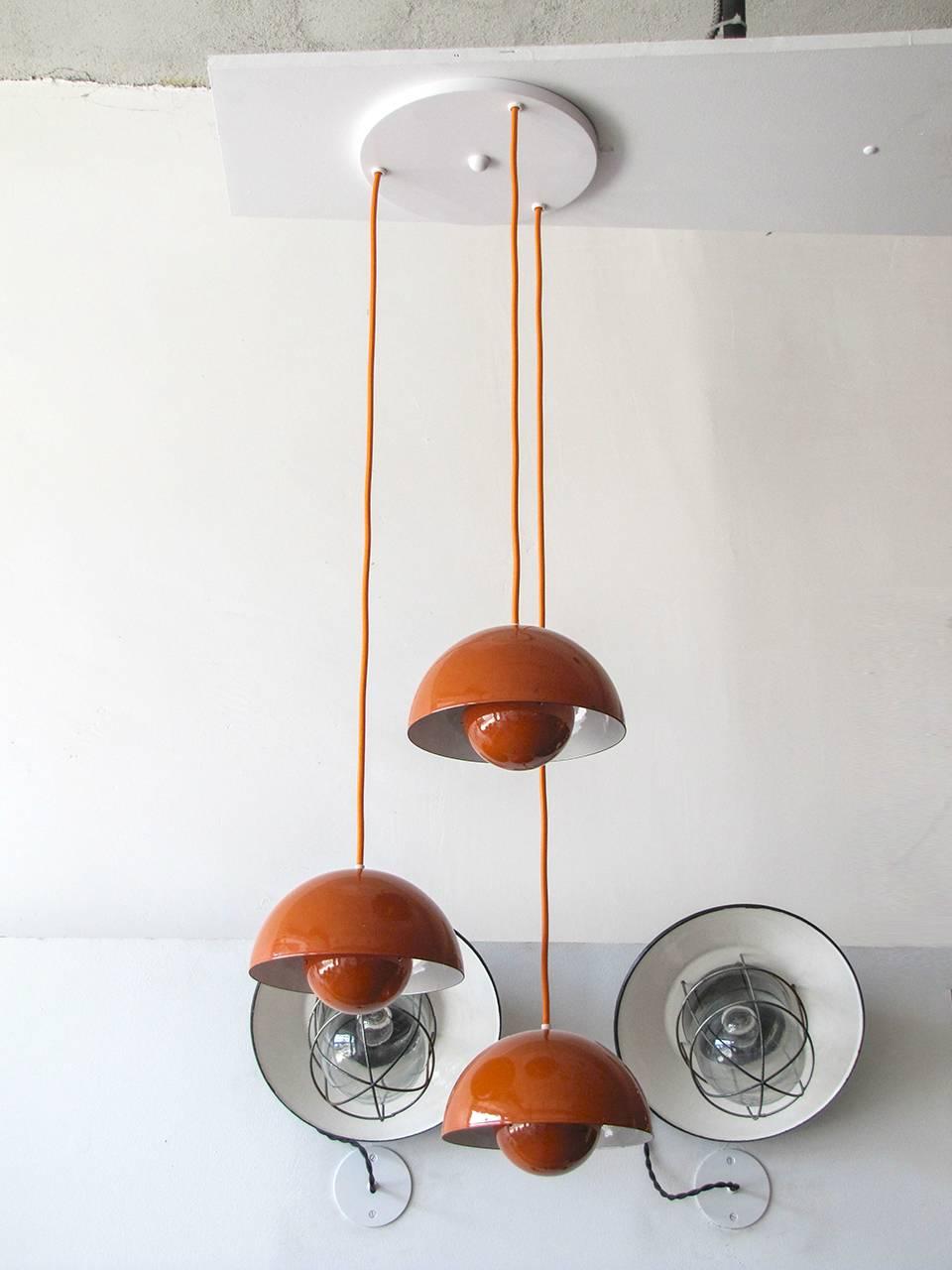 wonderful 1970's Flower Pot hanging lights by Verner Panton for Louis Poulsen, three orange enameled pieces with matching colored cords on a single canopy, insides of the reflector spheres is orange, heights are adjustable, a total of seven