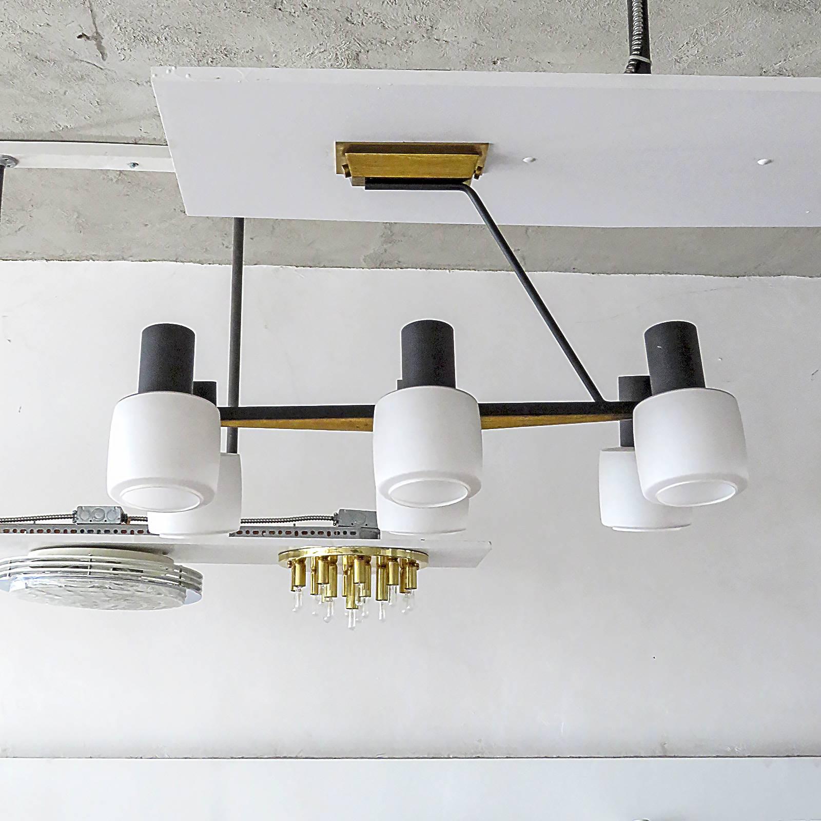 stunning french six light chandelier by Arlus, with six matte white cased glass shade holders branching off a cantilevering brass/black enameled metal main arm 
