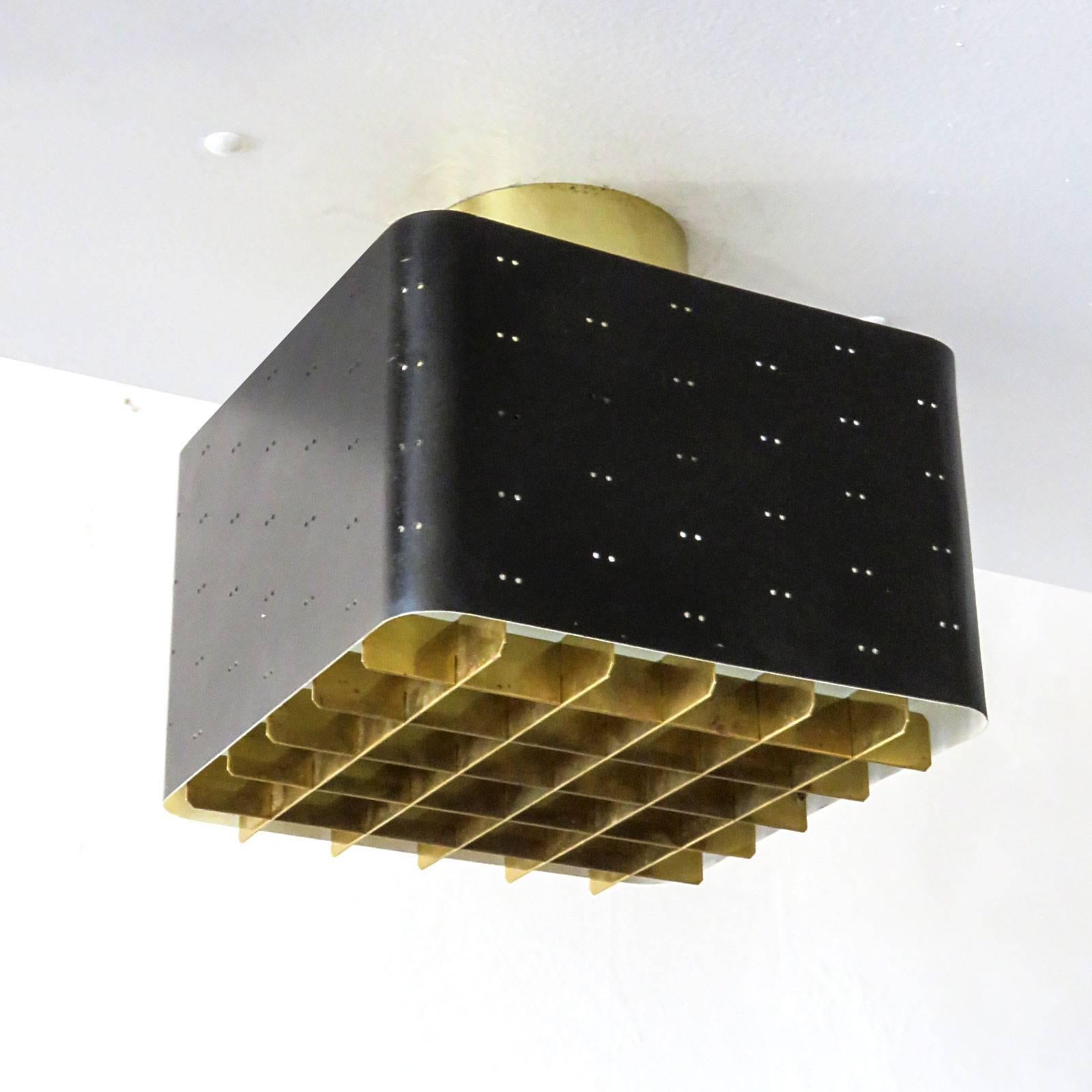 Stunning flush mount ceiling light, Model 9068, by Paavo Tynell for Idman, Helsinki, Finland, circa 1955, in brass and perforated enameled metal with frosted glass diffuser, stamped with manufacturer's label. Literature: Idman Oy catalog