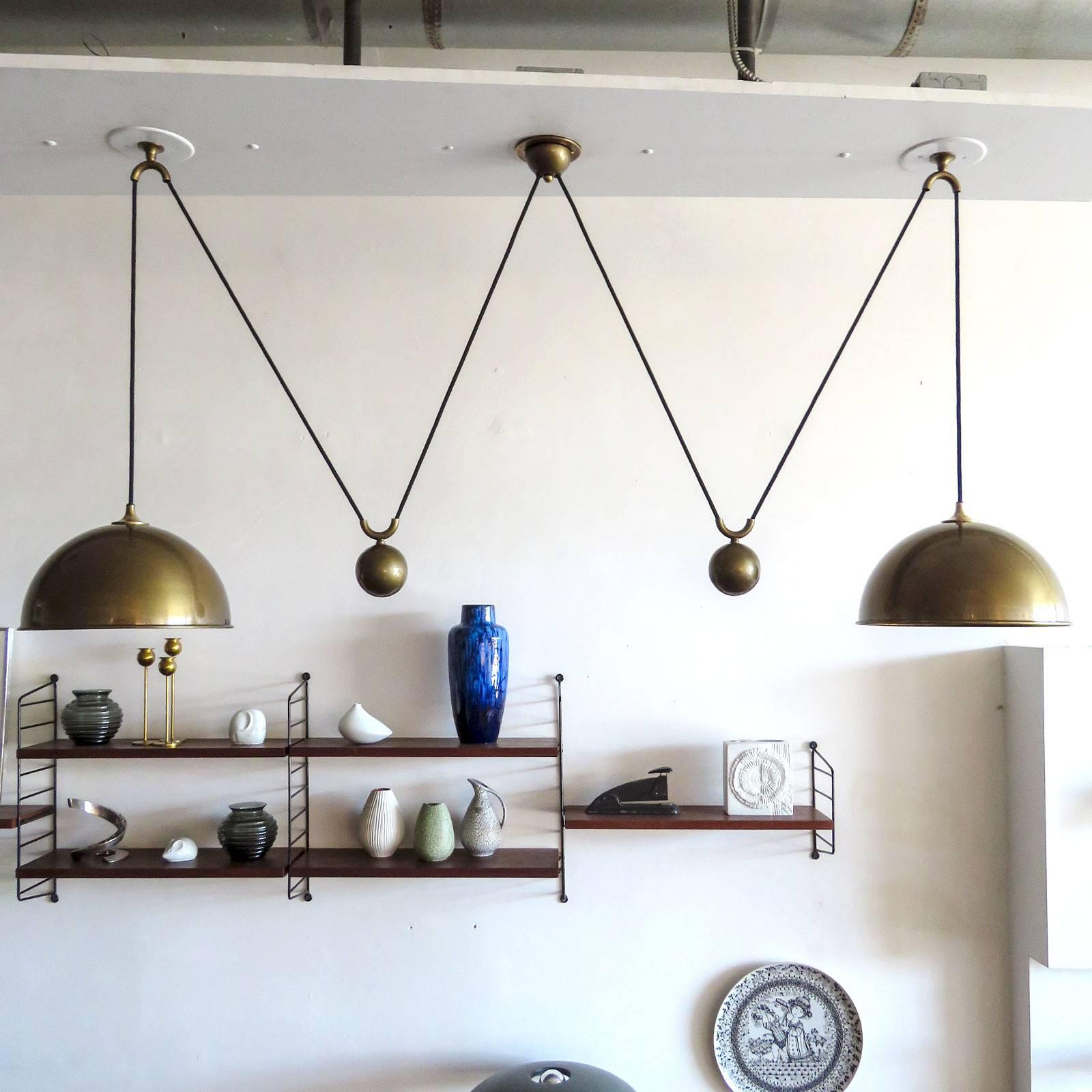 Stunning double brass counter balance pendant by Florian Schulz in great vintage condition, with two brass pendants suspended, each with their own very heavy brass ball counter balance pulley system and black cloth cord, supported by a single center