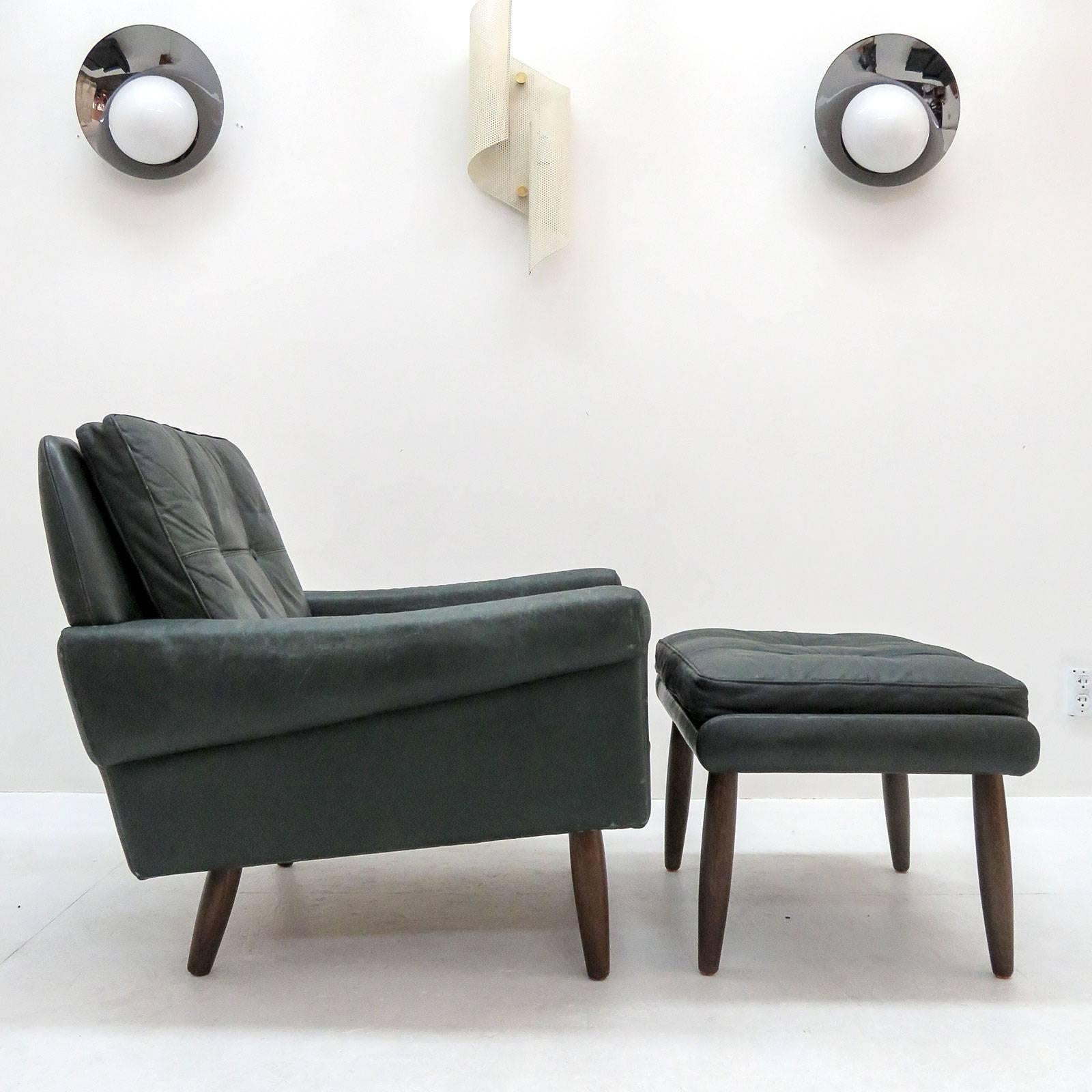 Wonderful leather armchair with ottoman by Svend Skipper, with loose cushions upholstered in buttoned patinated dark green leather with teak legs. Chair (H x W x D): 27.5 x 29.5 x 29.5, Ottoman (H x W x D): 16.0 x 24.5 x 17.0.