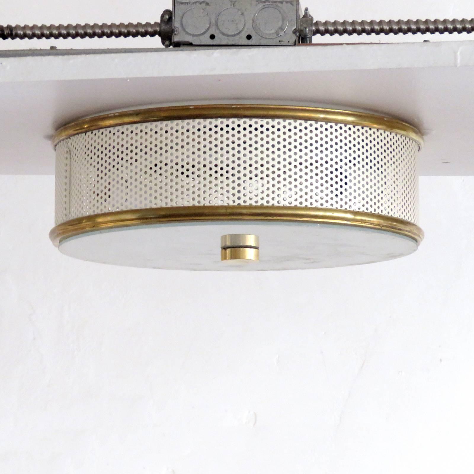 Elegant flush mount ceiling light attributed to Mathieu Mategot, perforated enameled metal ring with brass rims and sandblasted glass disc.
