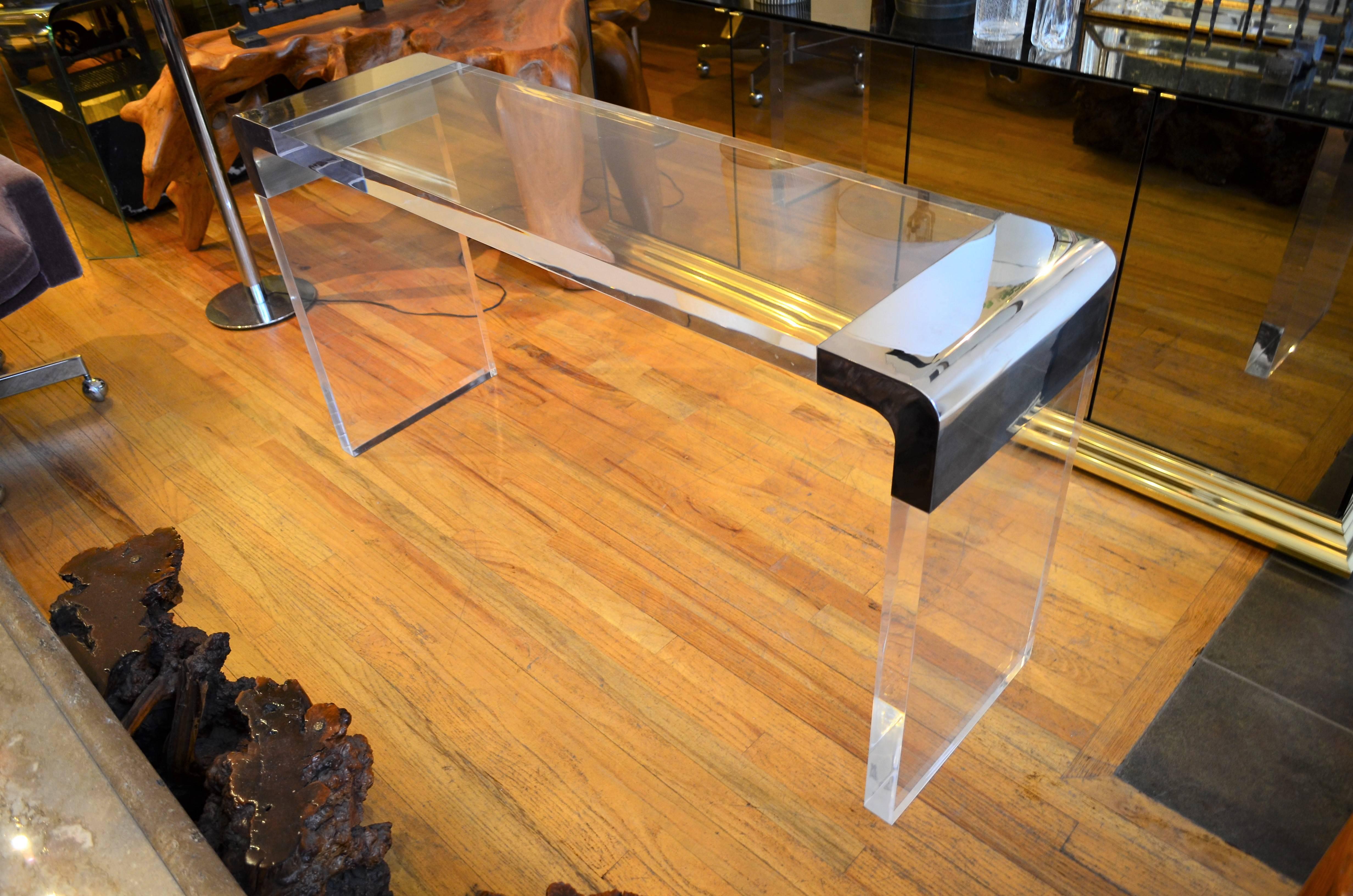 The finest 2 inch thick custom Lucite waterfall console table in the manner of Charles Hollis Jones. The substantial chrome ends are reminiscent of the Classic Pace tables. The table is in very good condition.