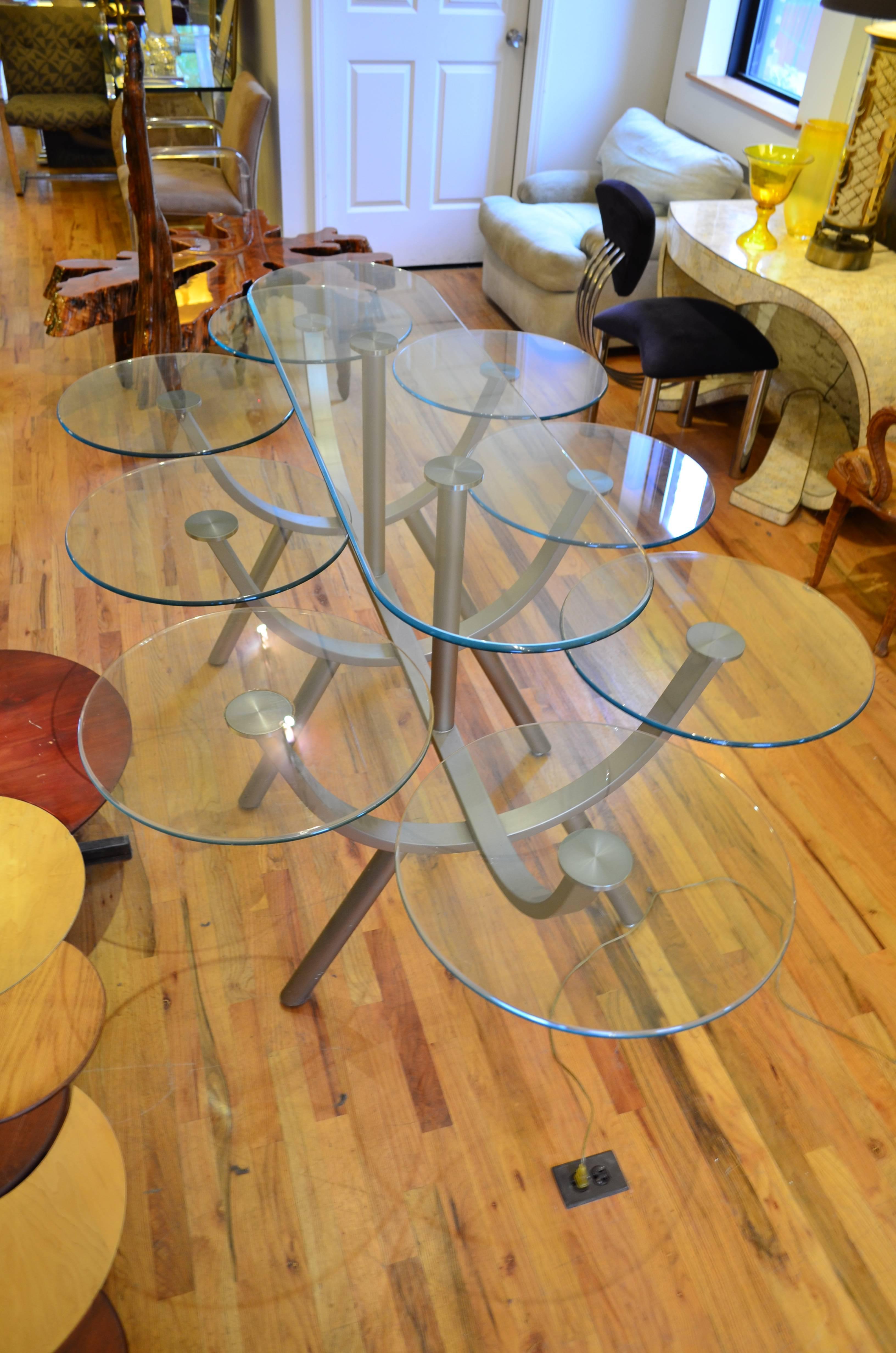 Glass Dining table from Design Institute of America's Circle of Life line.
The frame supports eight individual glass disks and one large 
raised center level which is 37 inches high. Dinner for eight.
Very good vintage condition with no chips or