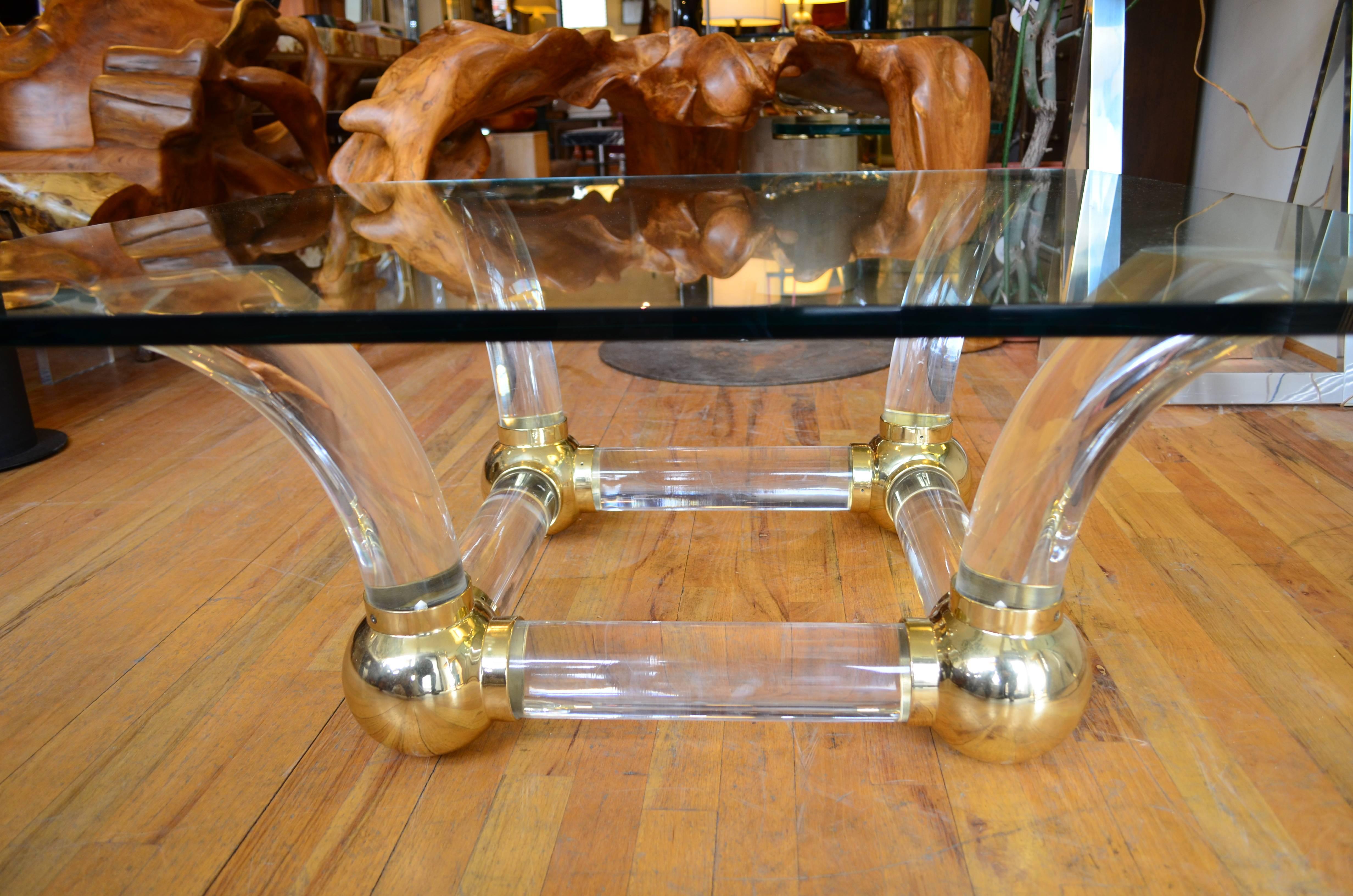 Lucite coffee table with brass ball 
fittings. The glass top is heavy and thick.