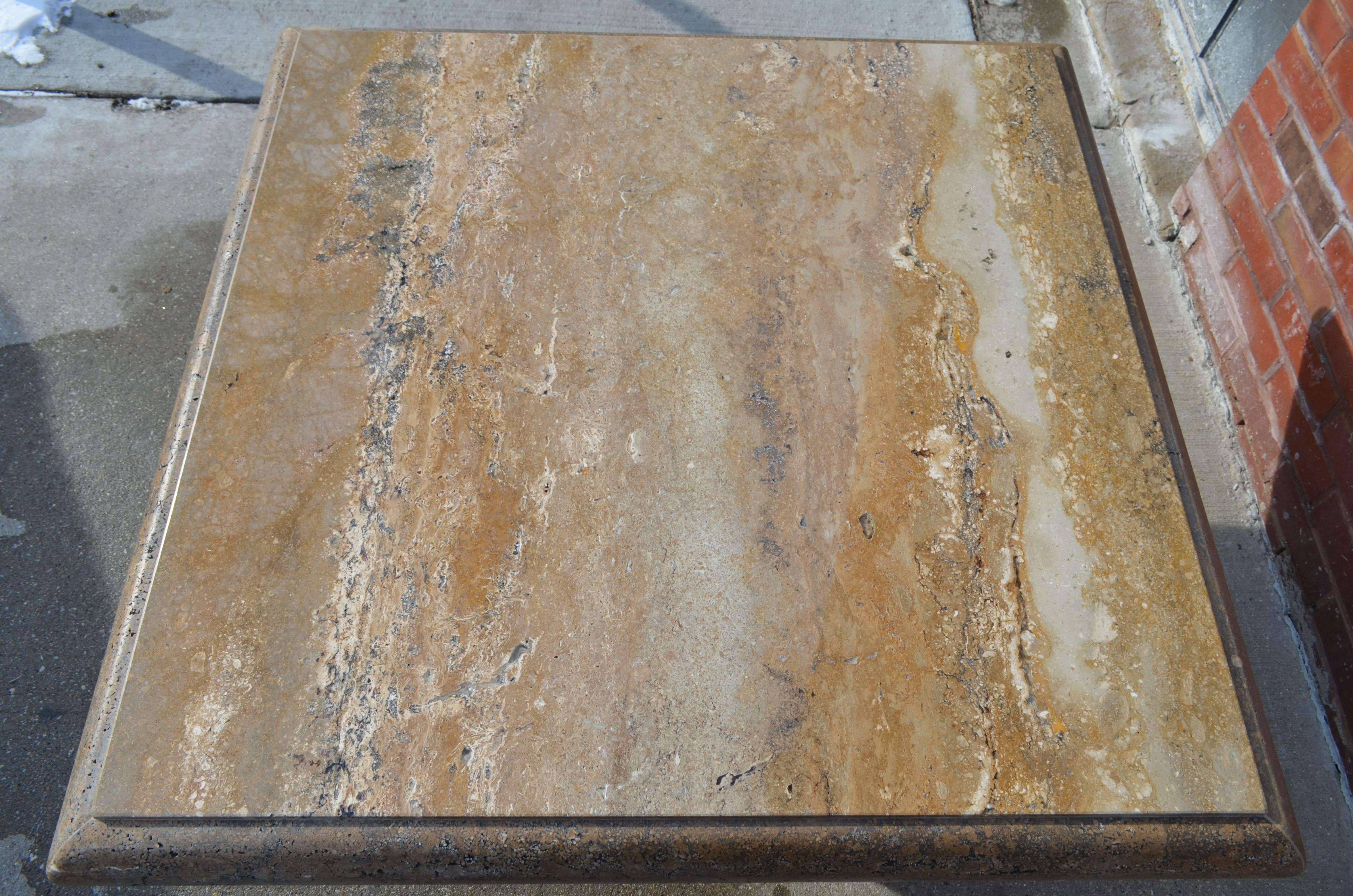 An Italian travertine coffee table on a pedestal base. The table has a rich active brown white and black grain pattern. Its sides are a generous unpolished deep bull-nose.