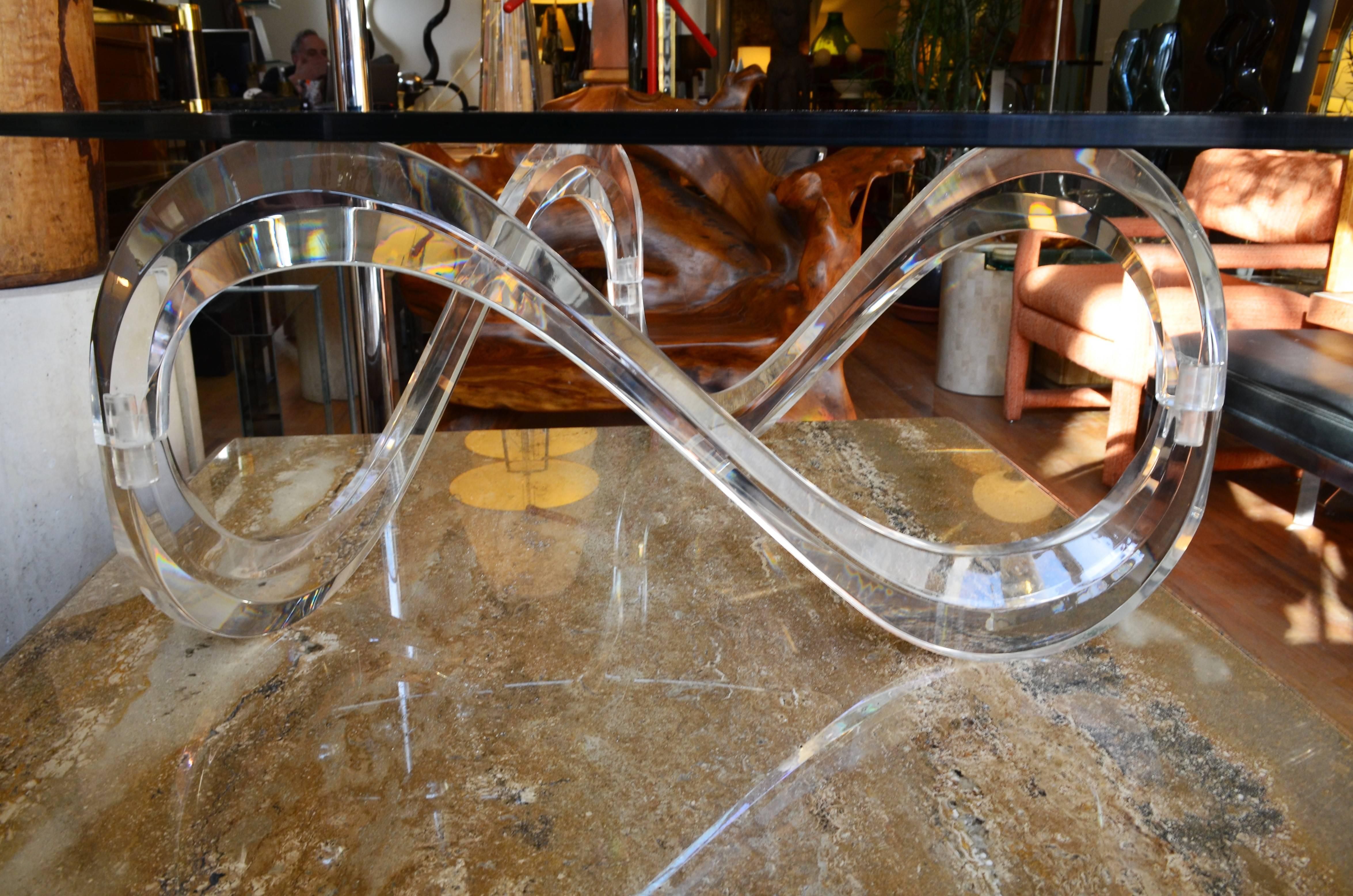 A fluid coffee table with a triangle infinity base. In the manner of Charles Hollis Jones the acrylic table has a kidney shaped glass top.