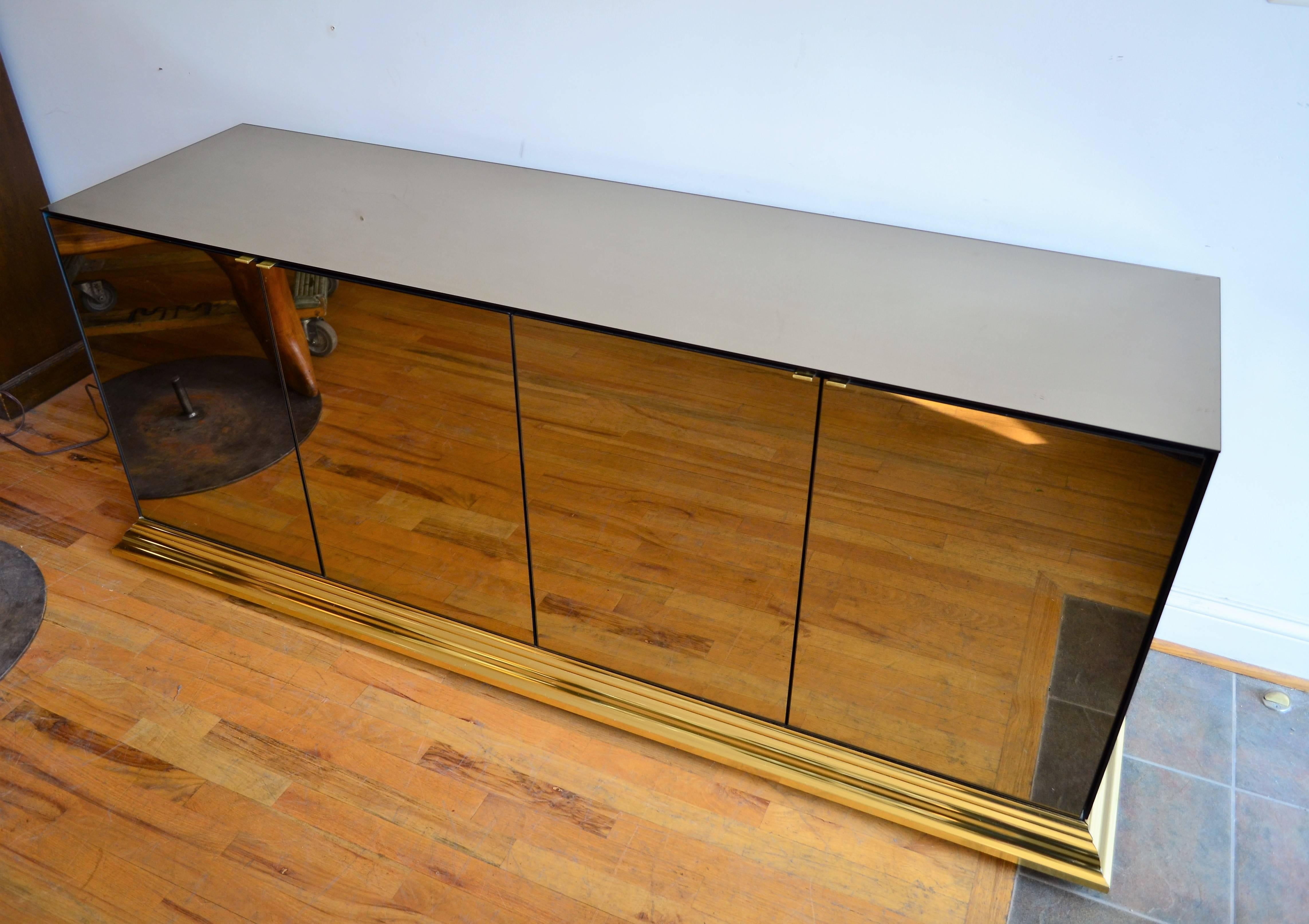 
An elegant bronze tinted mirrored buffet by Ello.
The cabinet is mounted on a brass base.