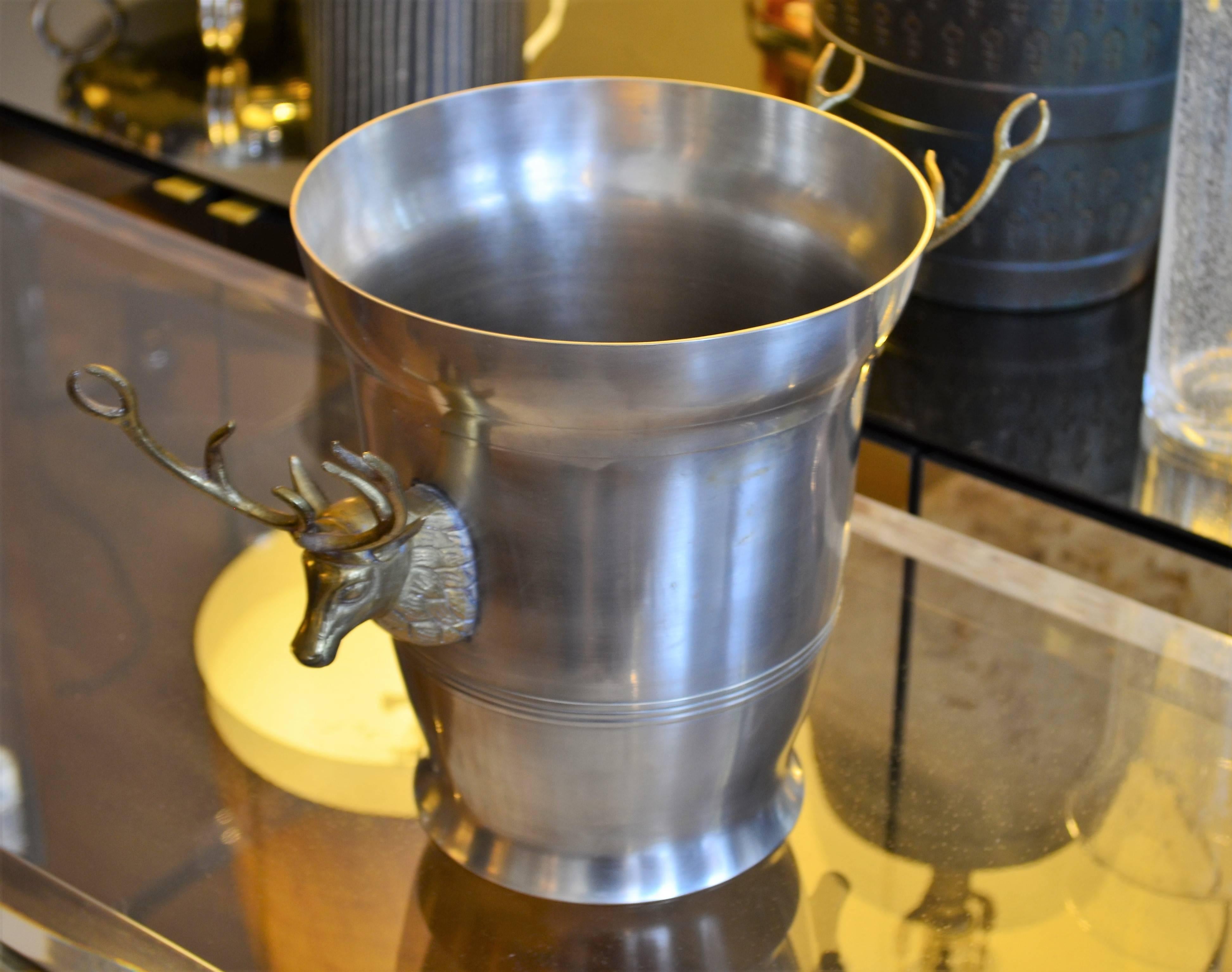 Highly decorative metal wine bucket with large-scale brass stag head side mounts. The champagne bucket is reminiscent of the Classic Gucci stag head stirrup cups. Fantastic festive barware.