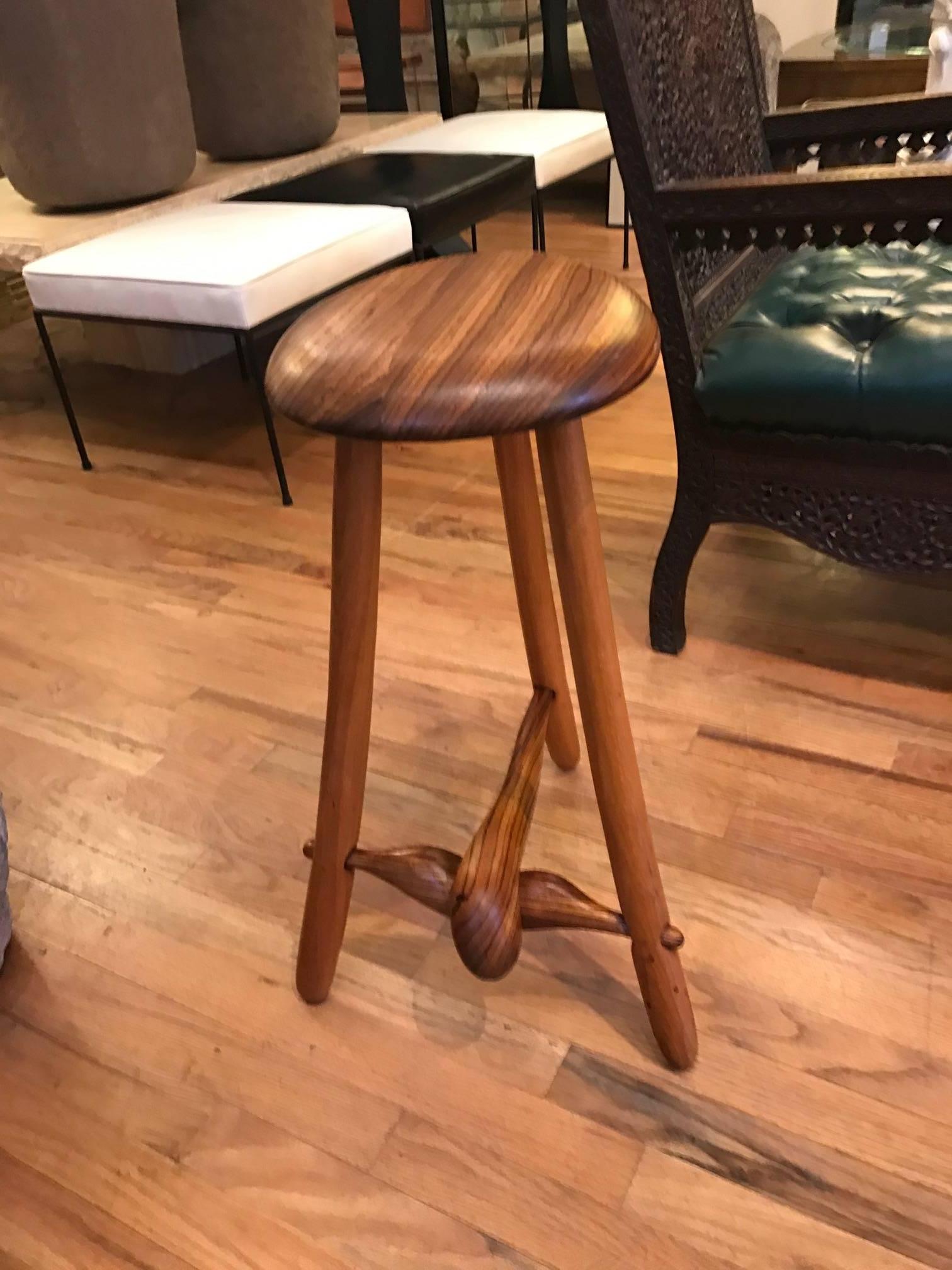 Walnut stool in the manner of Wendall Castle or Phillip Lloyd Powell. The richly grained seat is supported by three legs connected with bulbous nicely grained stretchers. Excellent original finish. Stamped Spiro 1985.
