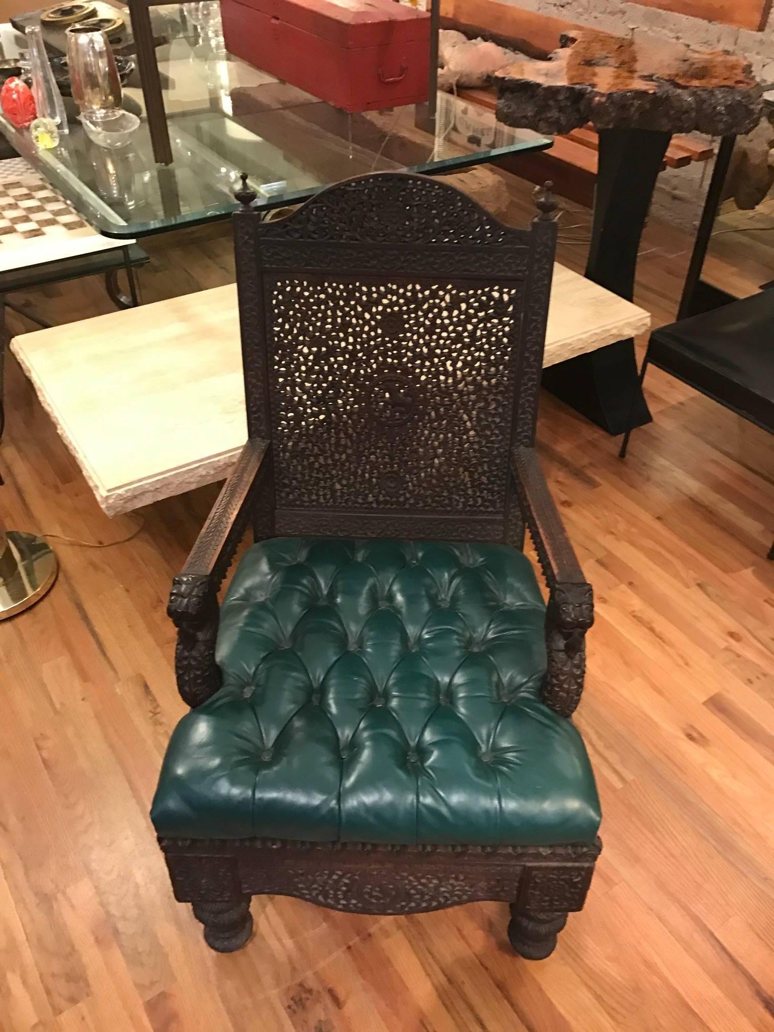 Anglo Indian arm chair with intricate carved stylized foliage throughout. The arms terminate in fanciful lion heads. Beautiful curved apron supported by baluster formed legs. The Chesterfield tufted style seat is upholstered in supple leather.