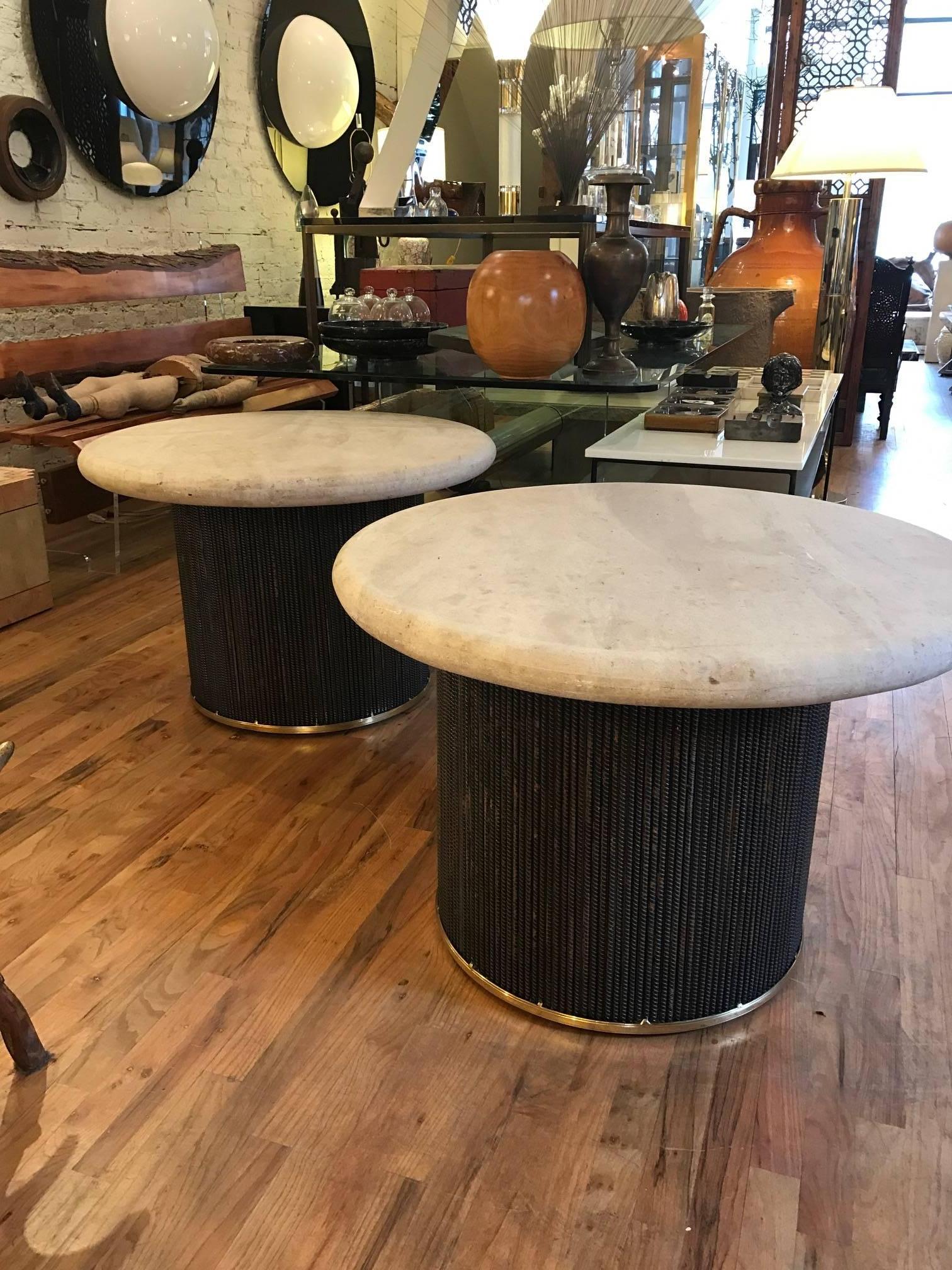 Round  Travertine and steel pair of end tables. The honed Travertine tops are 2.5 inches thick. The bases are made of bound steel rebars with a brass band on the top and bottom. A pair of incredibly chic well made side tables.