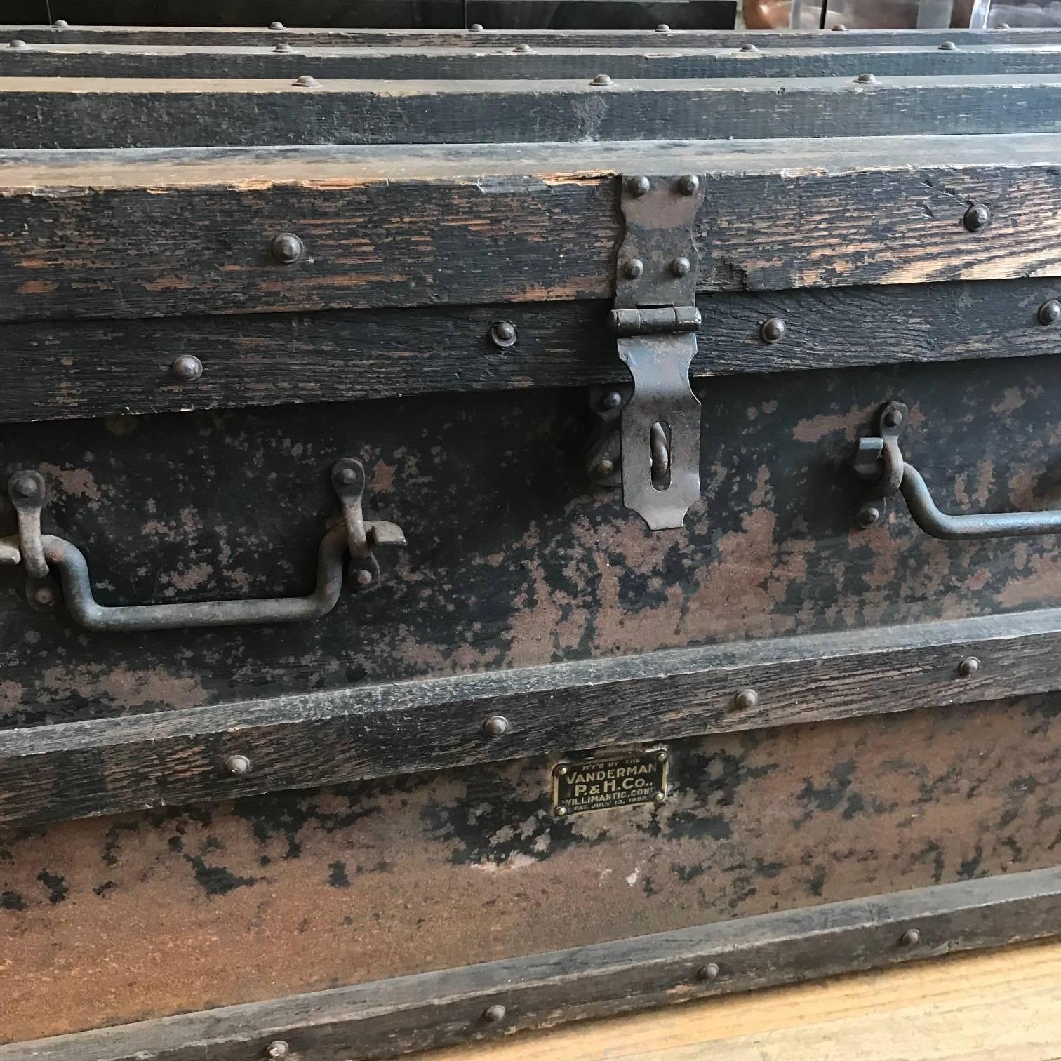 Industrial wood trunk with iron and metal embellishments. The metal strapping is enhanced with ornamental trim, tacks, and iron corner brackets. The handles on all four sides are crafted of hand-forged iron. Manufactured in 1897 by the Vanderman P&H