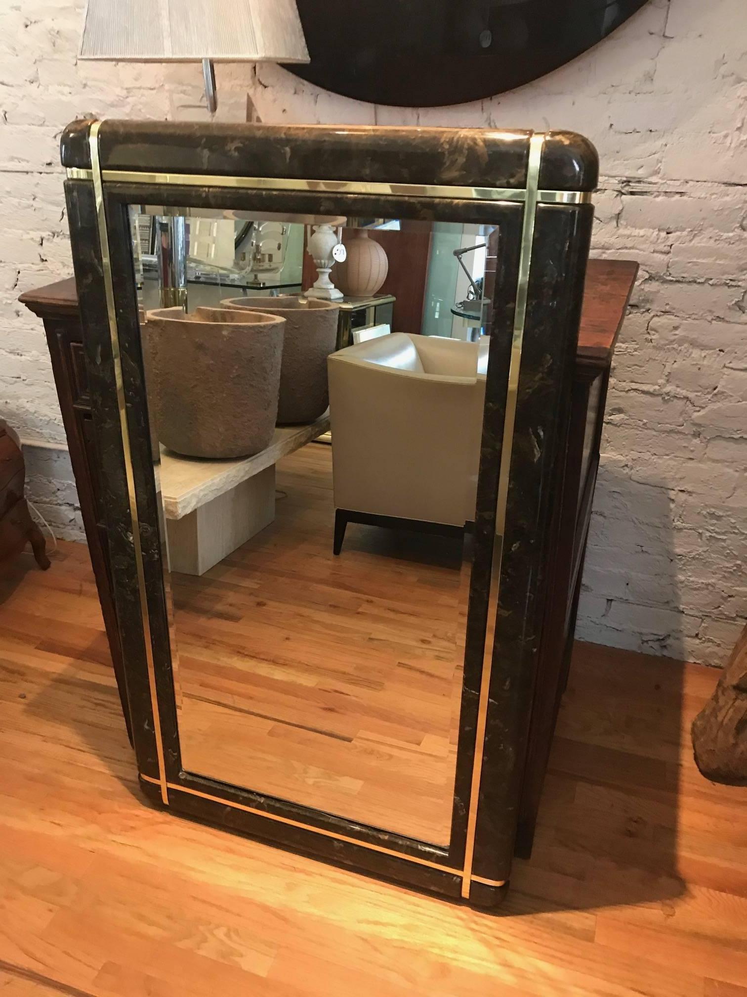 An elegant Karl Springer style mirror with a brown marble frame and brass banding.
Finest quality craftsmanship.