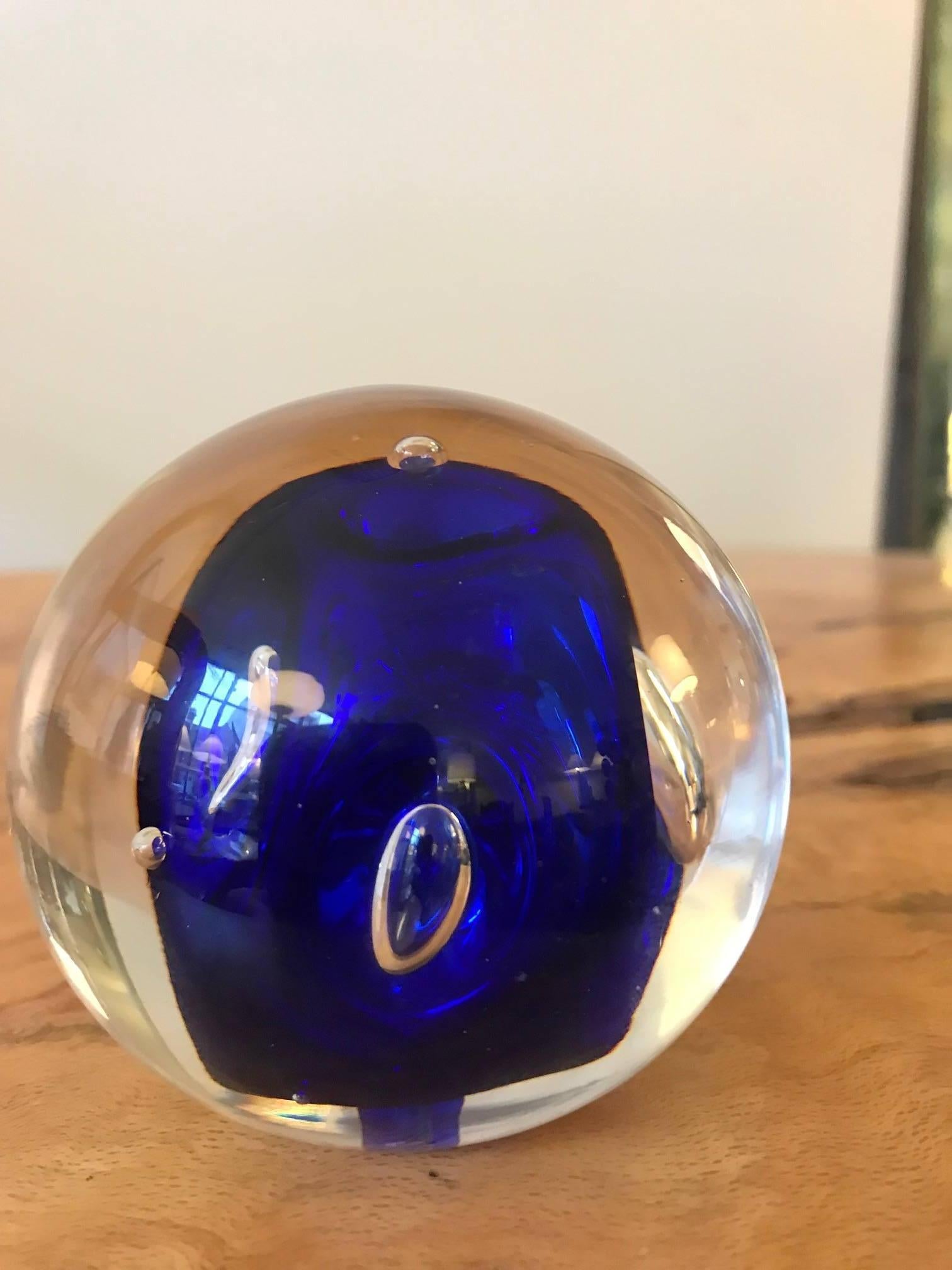 A Murano art glass round glass paperweight with cobalt blue and bubble inclusions.
Fantastic decorative tabletop object. Signed CA.KY to the underside.