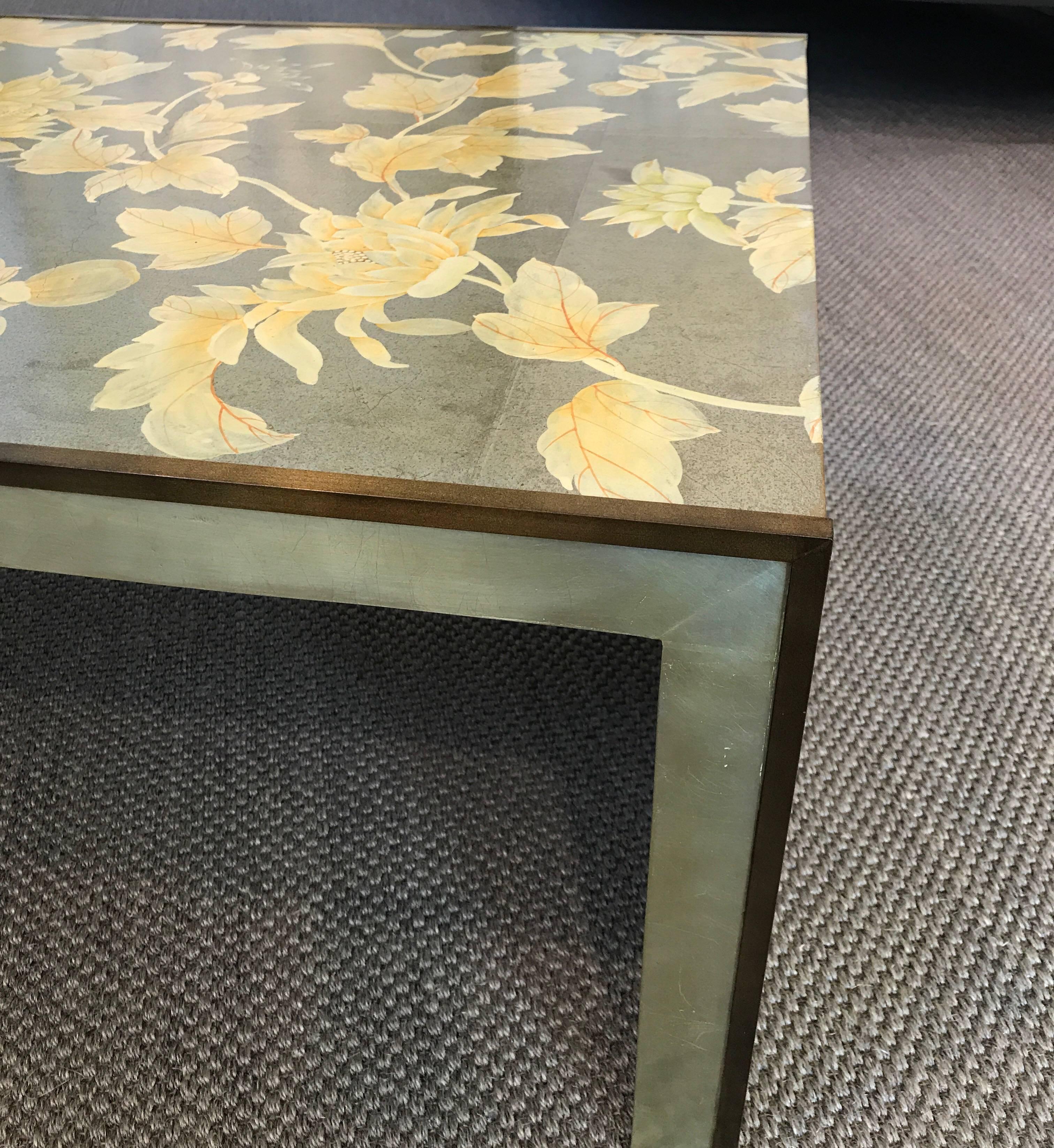 A Parsons style waterfall coffee table, with metal edges. The design is a hand applied vintage 
Gracie hand-painted wallpaper on silver leaf. The edges of the table have bronze metal edges, and the table has a cashew lacquer finish.