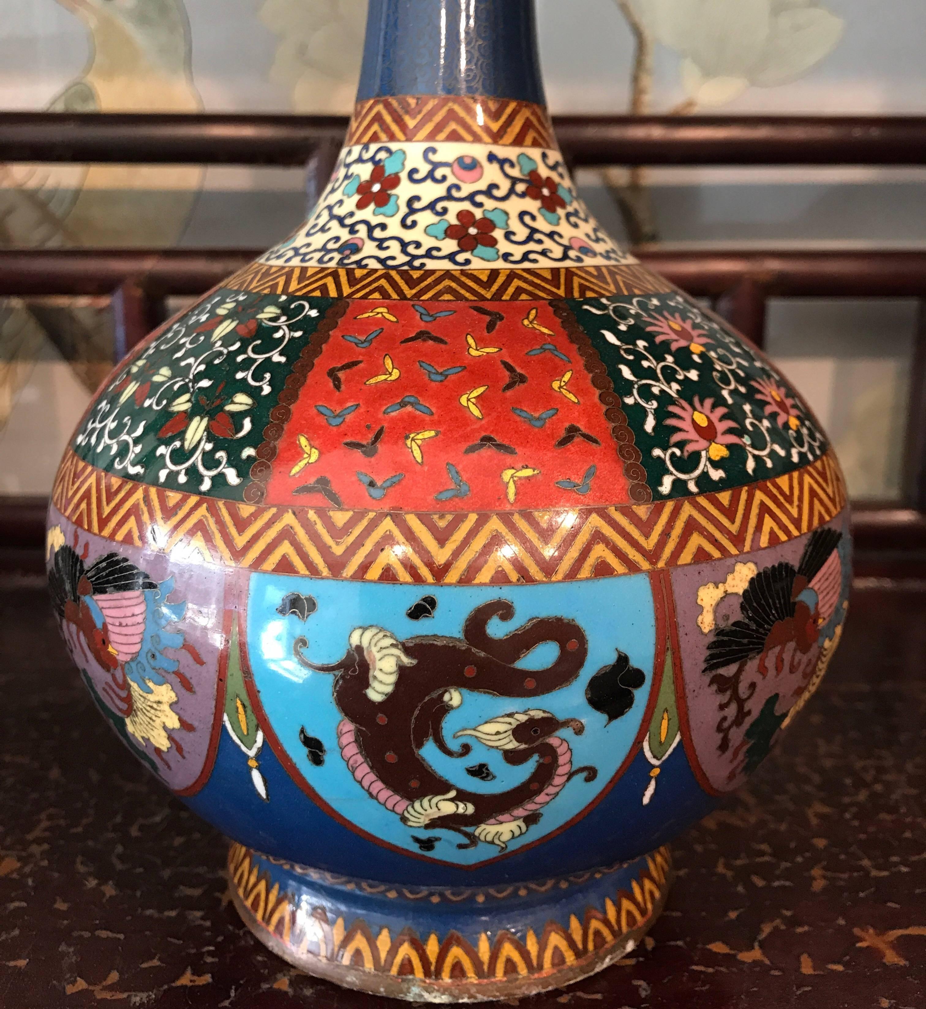 A matched pair of Japanese cloisonne vases in exactly the same shape and size, but with different colors and design patterns. Both have highly detailed geometric and other patterns, with dragons.