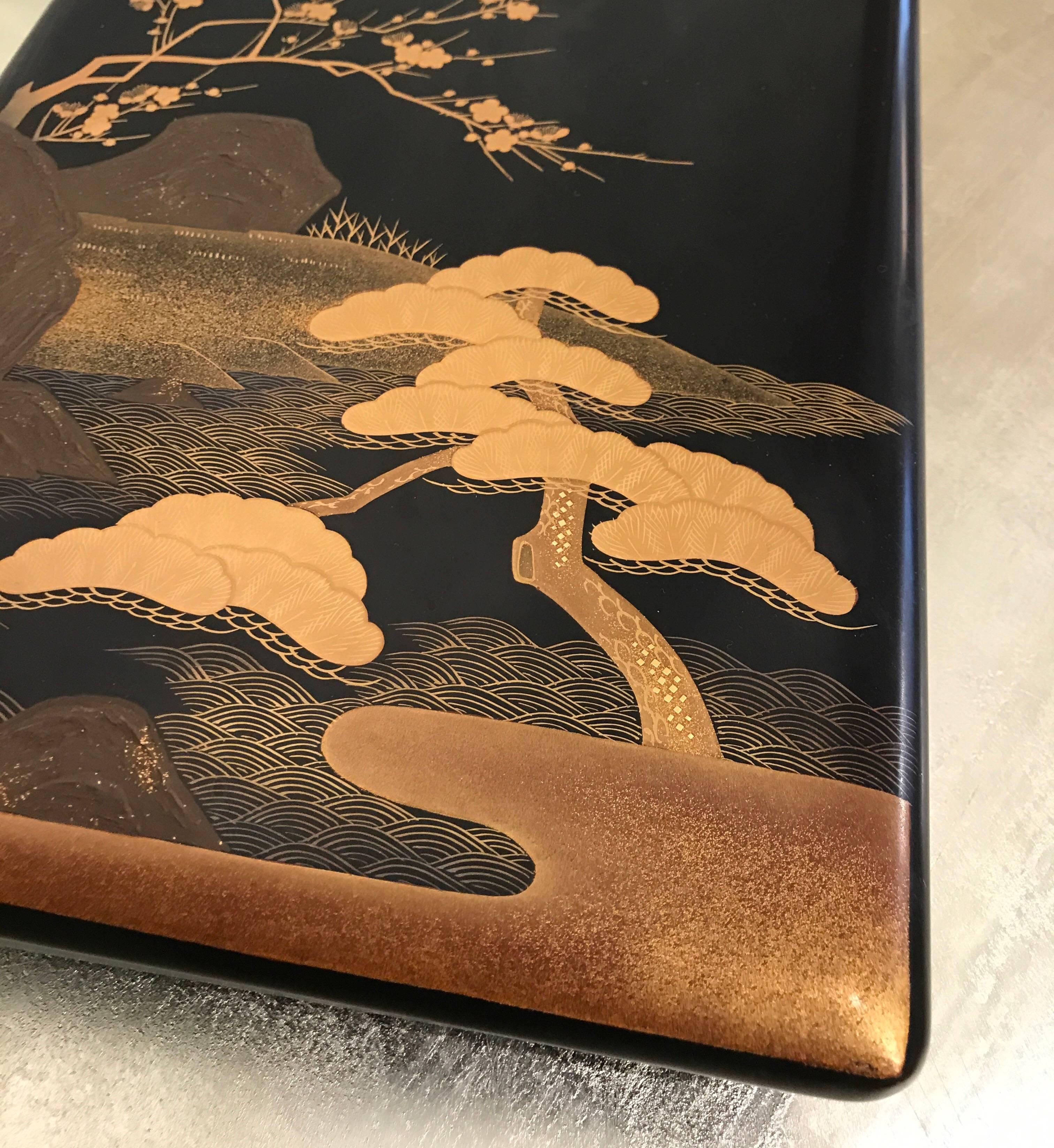 Early 20th century Japanese black lacquer box with design of cherry blossoms, pine trees and water.