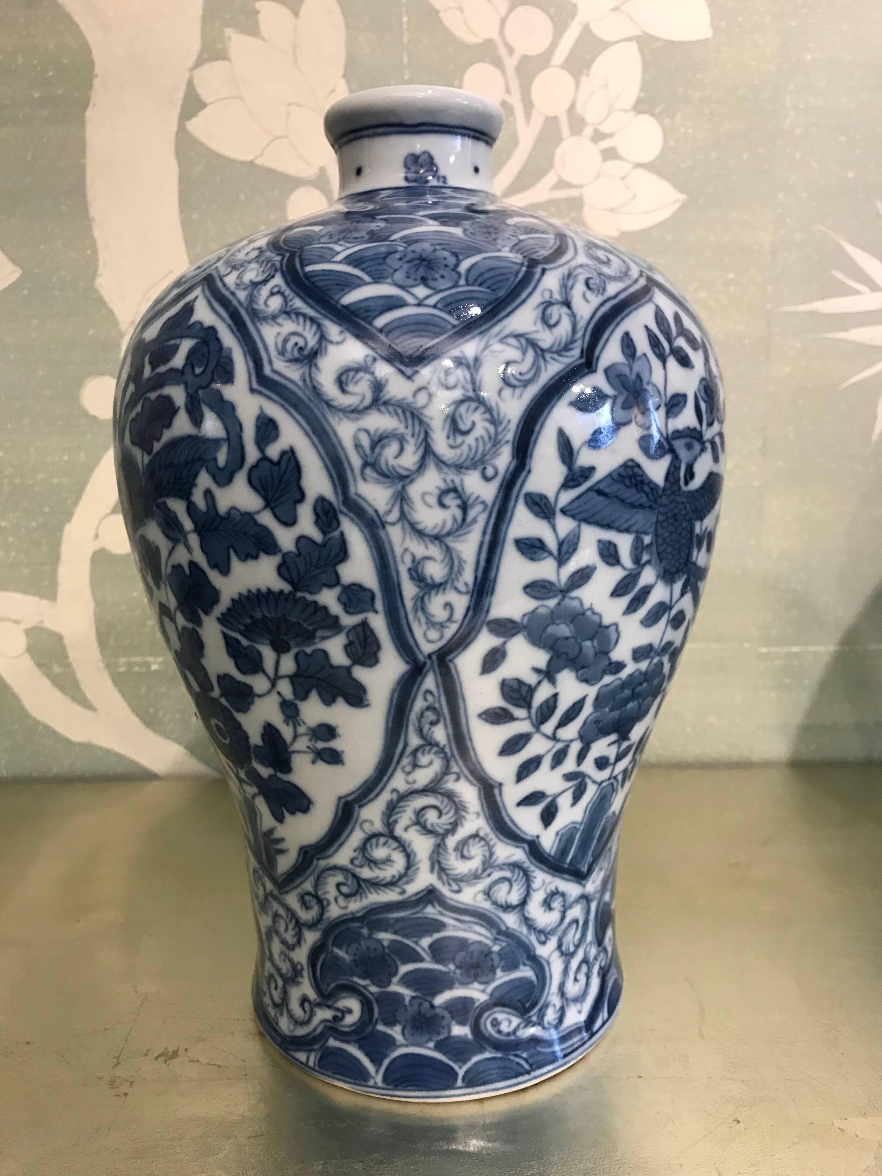 Pair of Korean mid-20th century blue and white vases with reserves of birds, flowers, and wave borders.