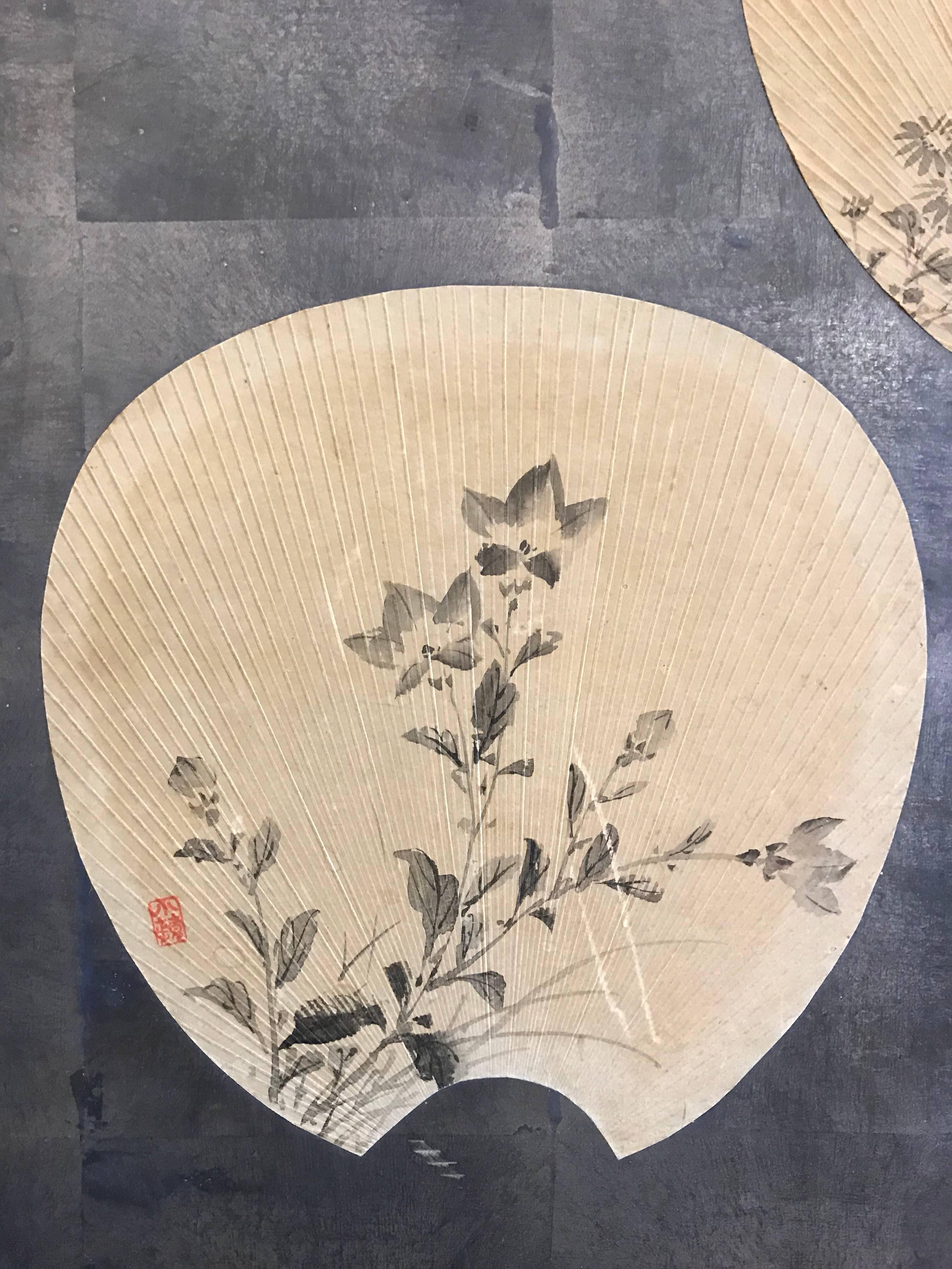 A beautiful two-fold antique Japanese screen with silver leaf background, and design of scattered fans.

Fans have various floral patterns. The screen has a traditional black lacquer frame.

Measures: Each panel is 35