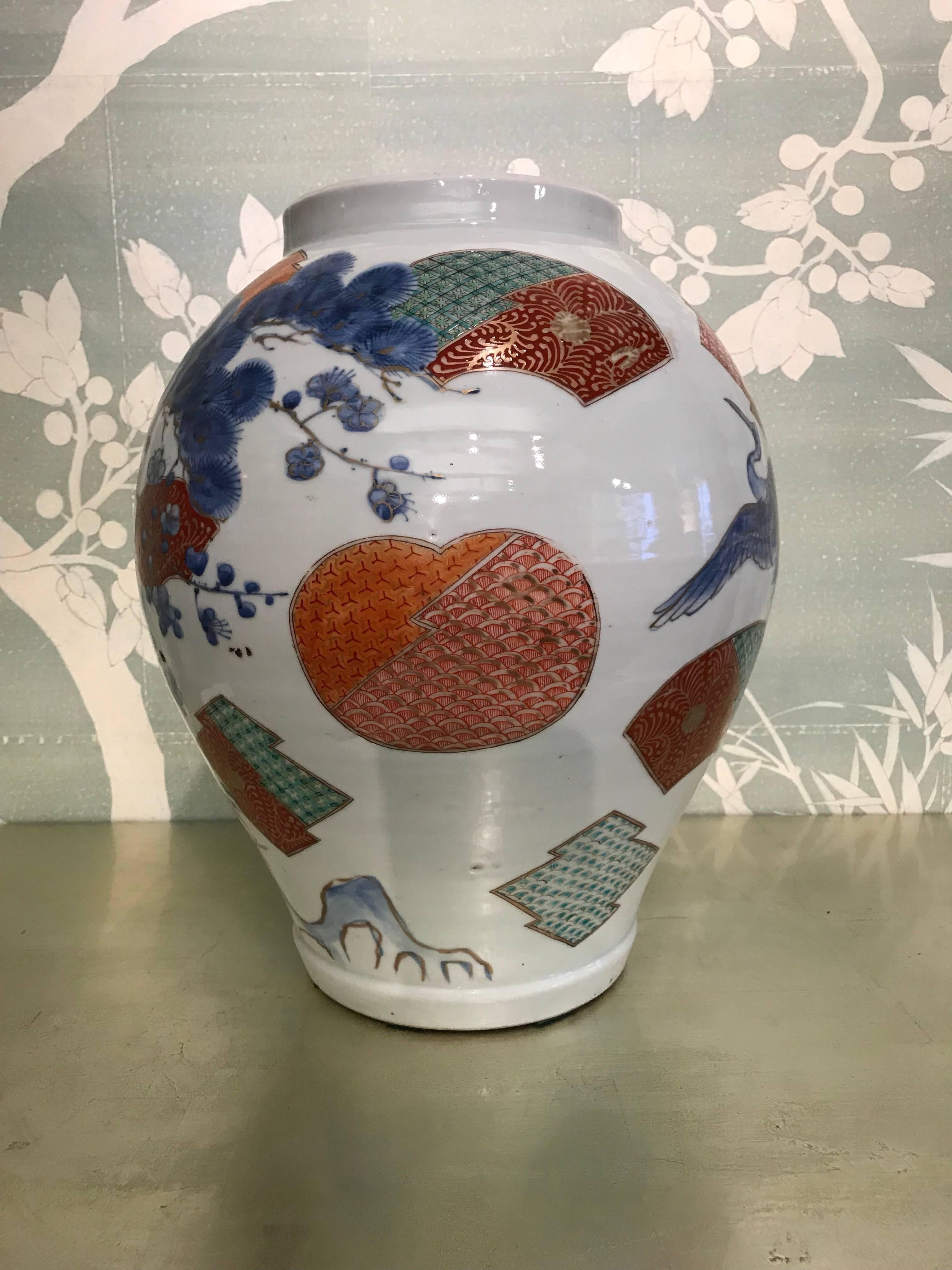 A large early 20th century Japanese Arita jar with beautifully detailed design of pine tree, cranes in flight, and scattered fans.