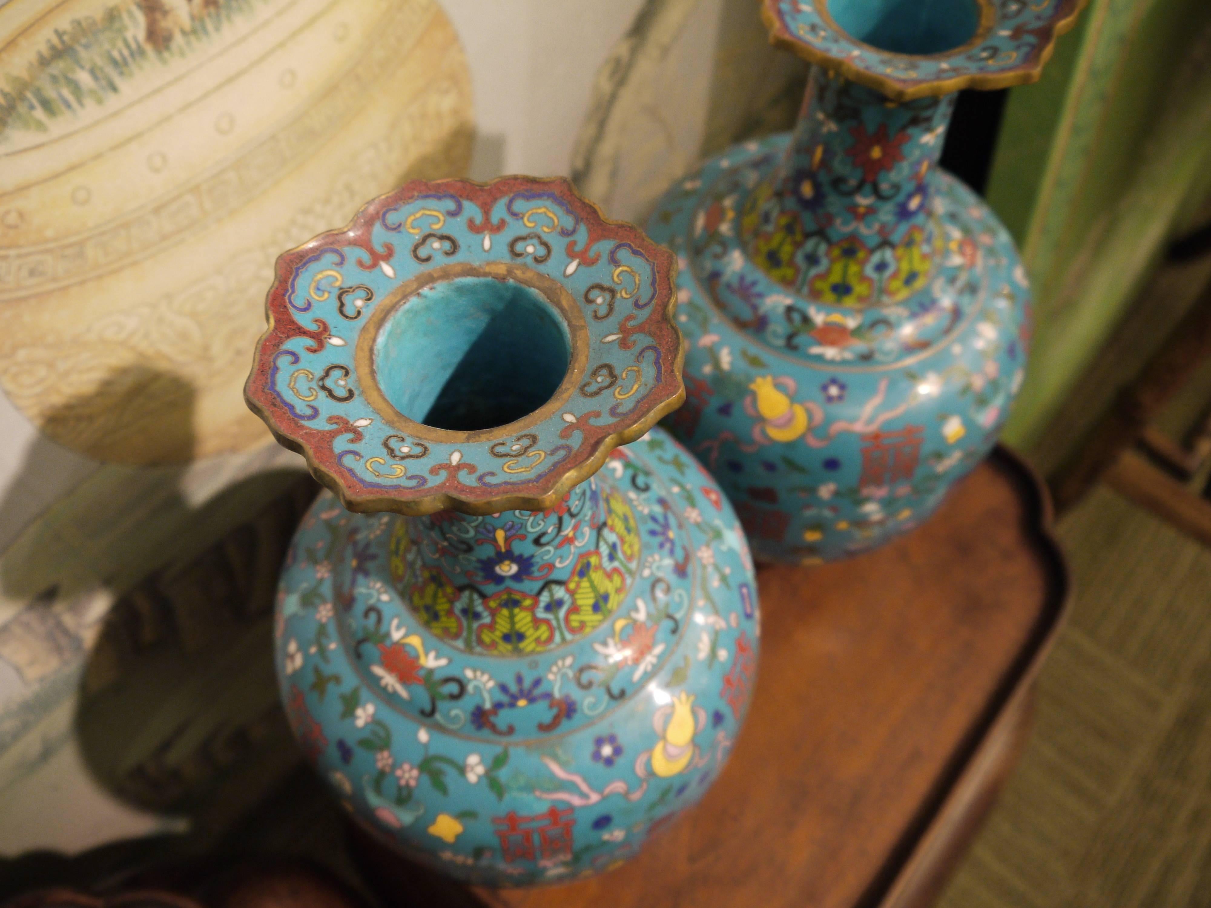 A graceful pair of vint Chinese cloisonné bottle shaped vases, with design of vases and flowers, and ornately shaped tops.