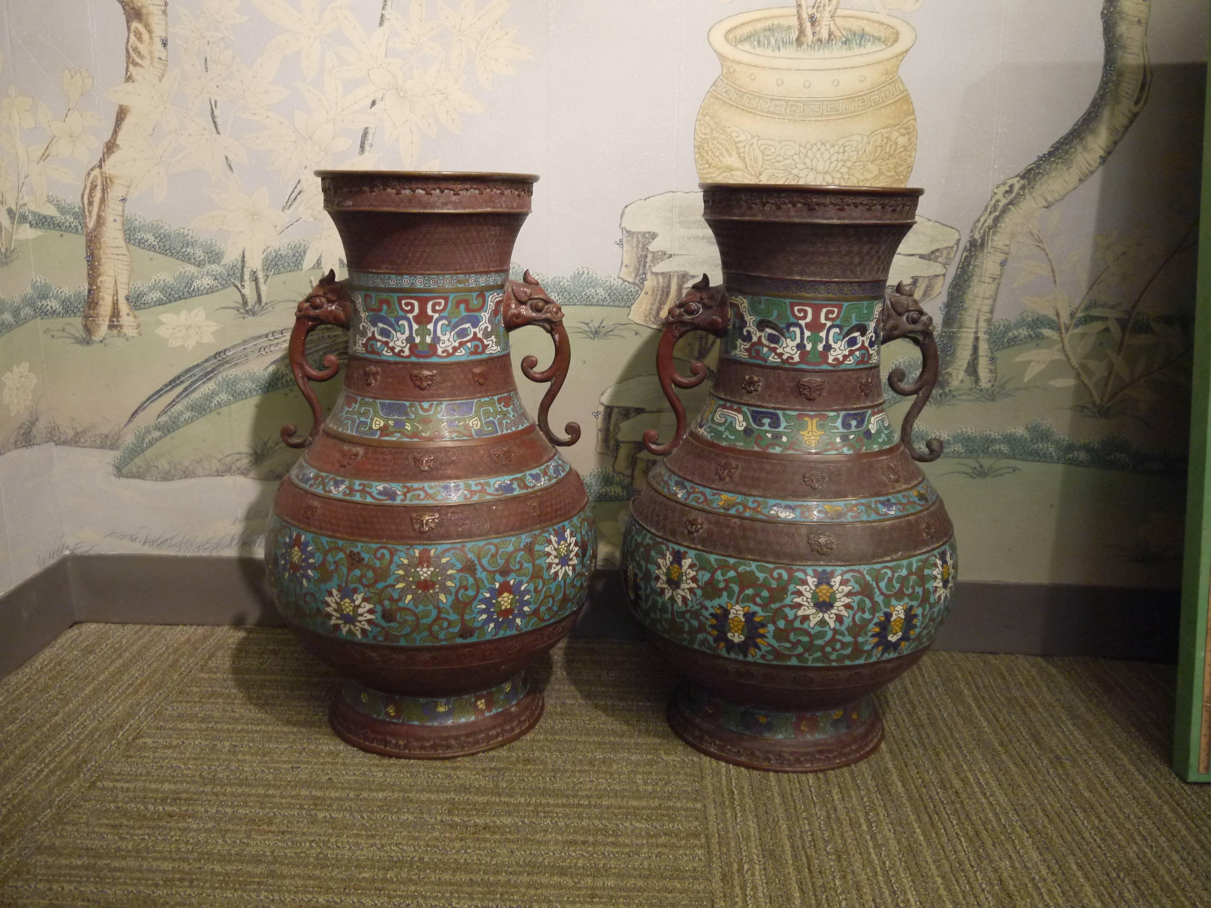 Turn of the 20th century pair of metal vases with inlaid enamel design in bands of bold patterns, with lion handles.