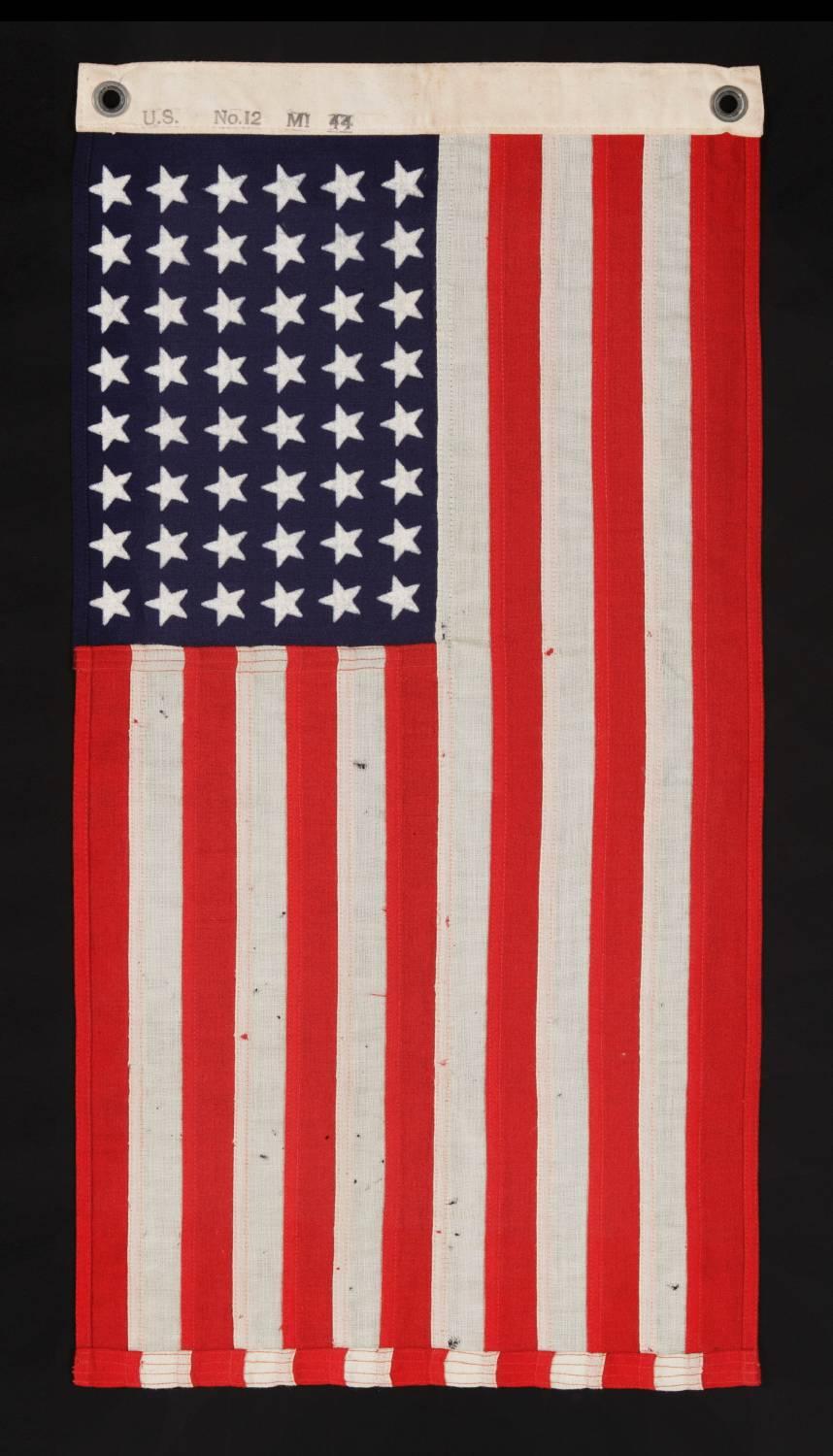 48 star, U.S. Navy small boat ensign, made at Mare Island, California during WWII, signed and dated 1944, in the smallest scale employed at the time. 

48 star American national flag, made during World War II (U.S. involvement 1941-1945) and
